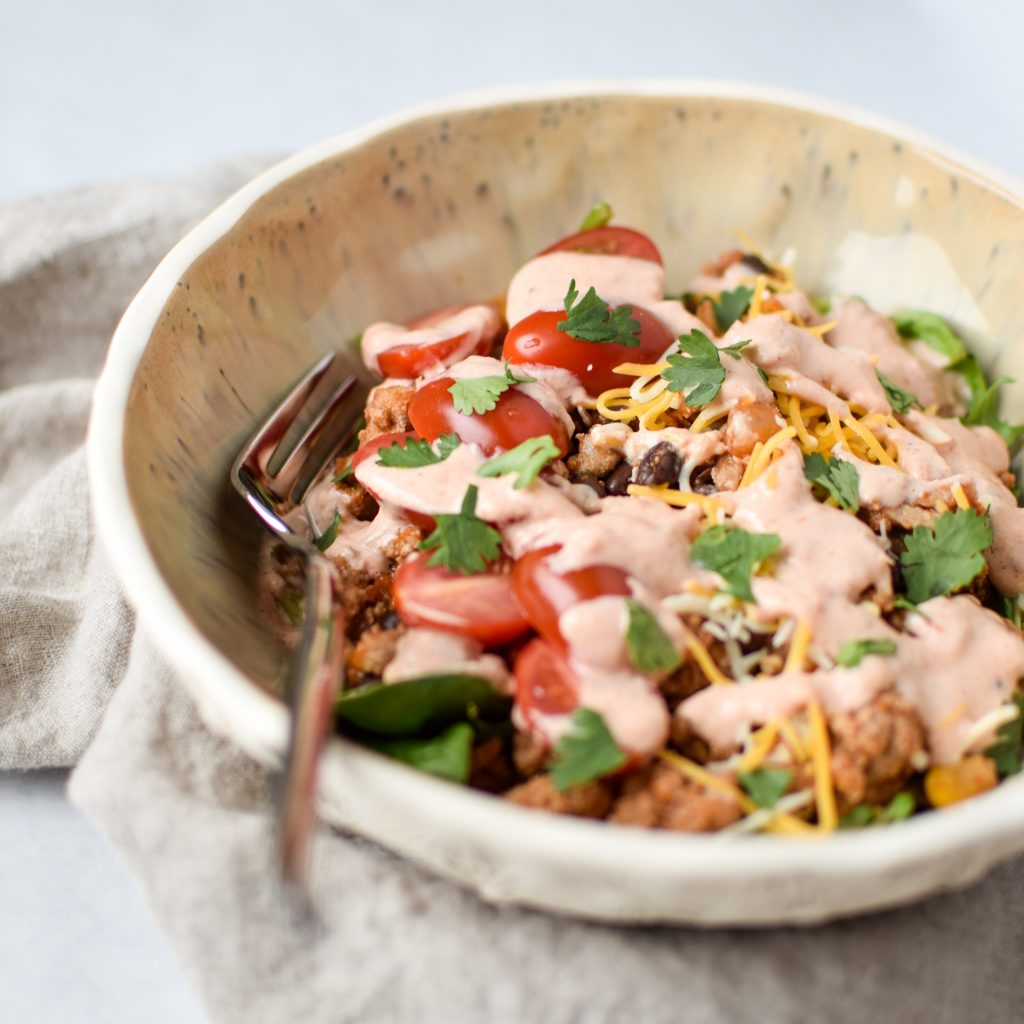 meal prep turkey taco black bean salad in a bowl with dressing and cilantro on top.