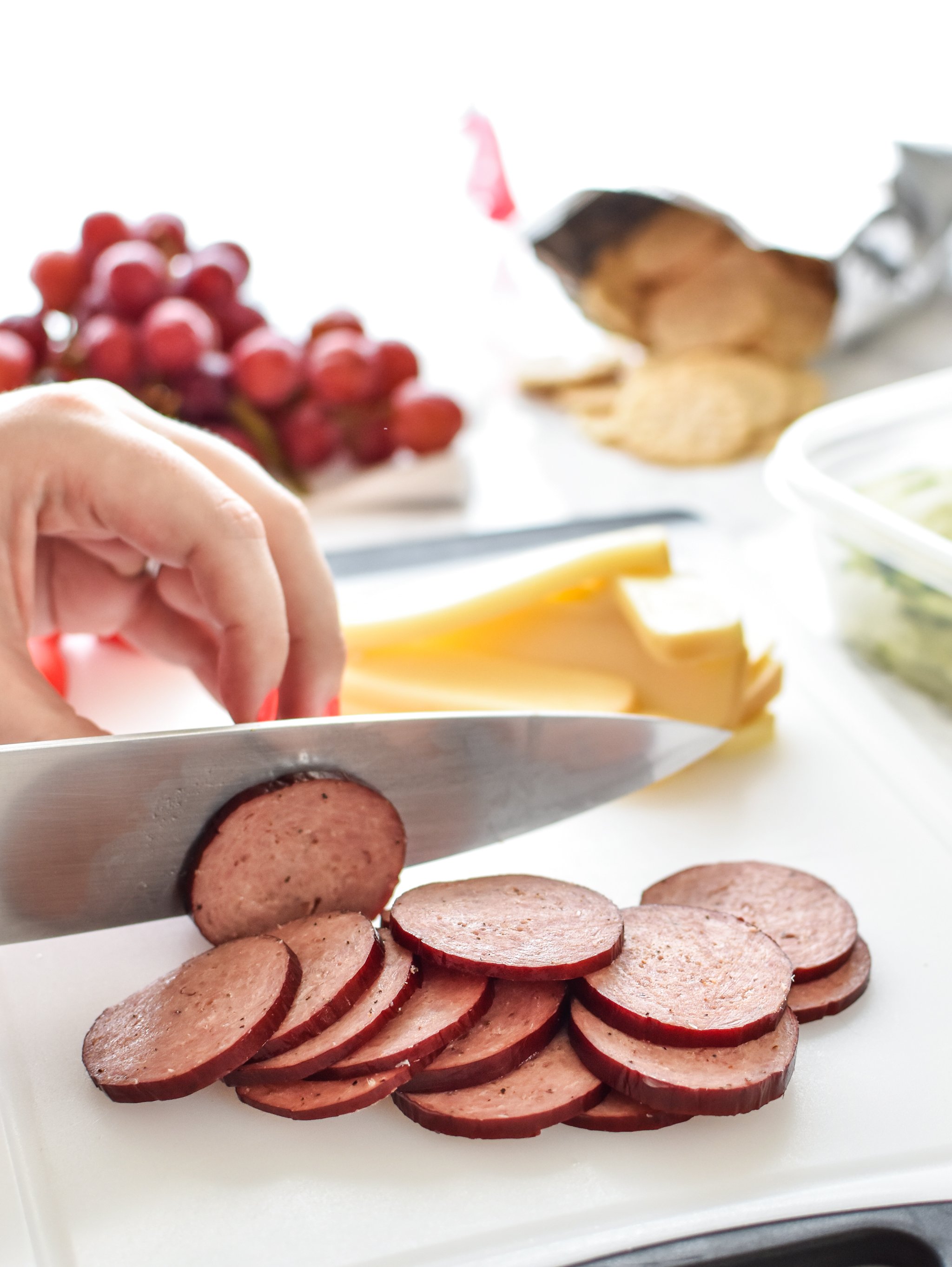 How to Turn Cheese and Crackers into DIY Adult Lunchables - Cutting up some turkey summer sausage for my adult lunchables.