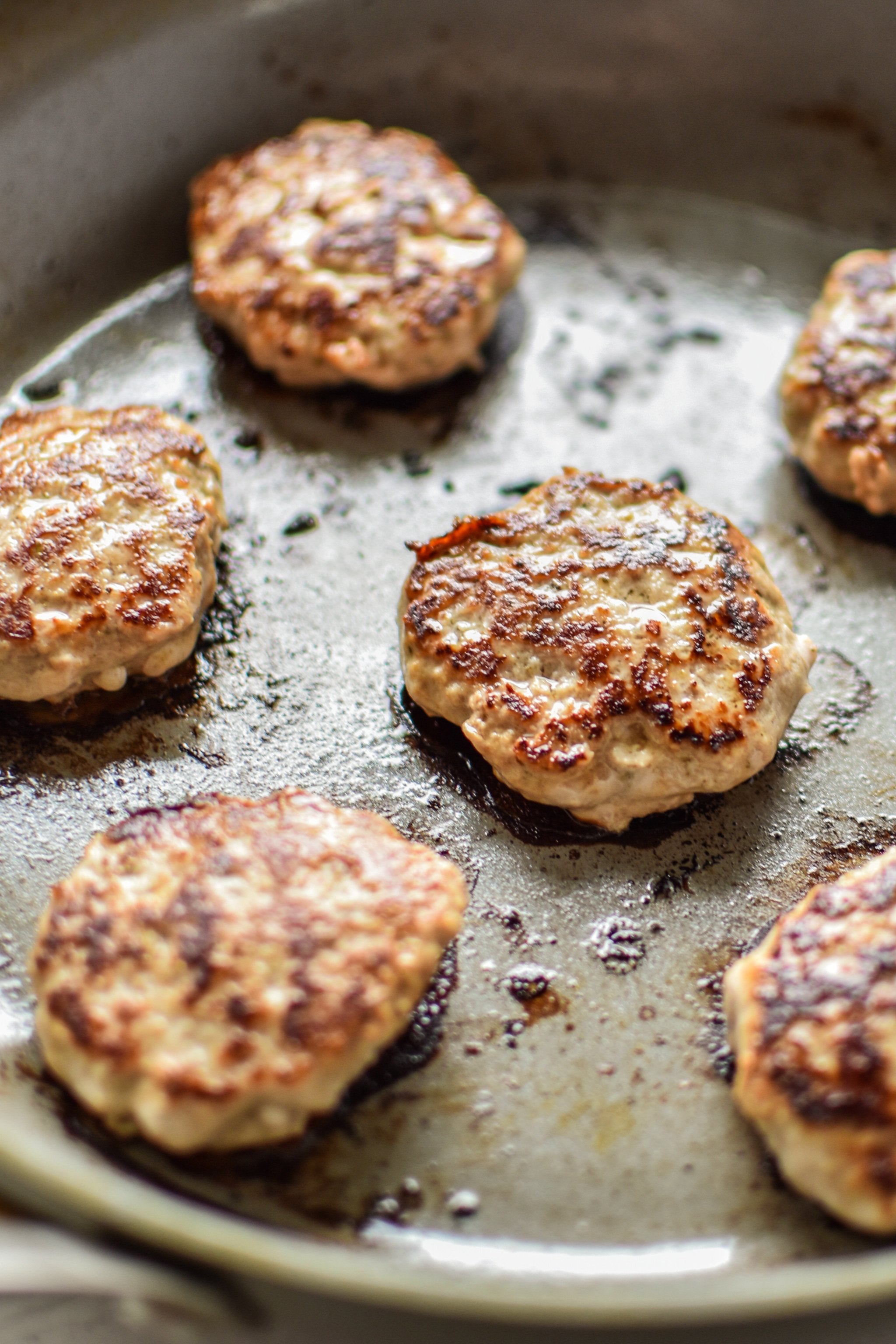 Ground turkey breakfast sausage patties frying in the pan.