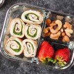 A turkey pinwheel meal prep with berries and nuts.