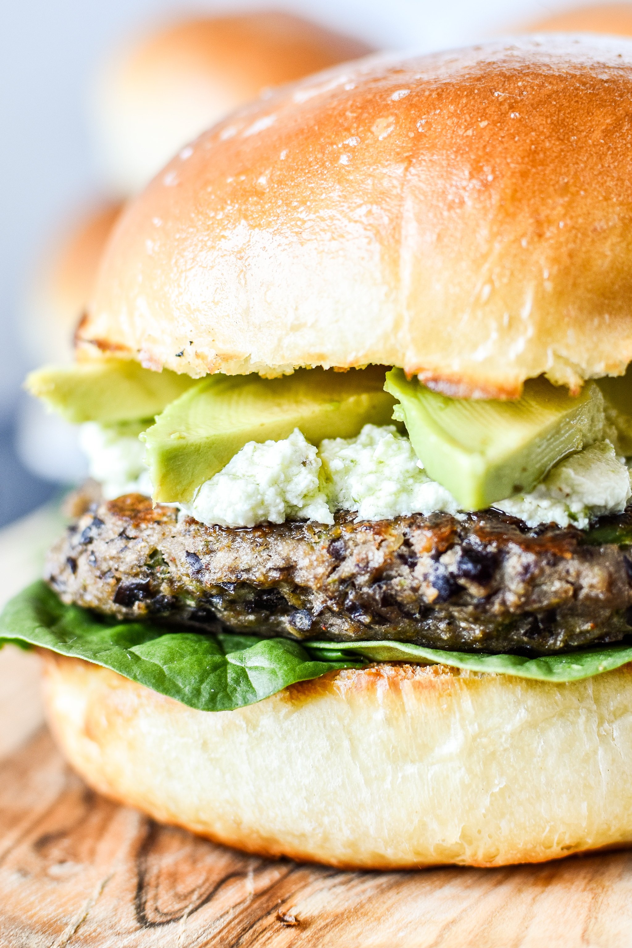 A freezer friendly black bean burger with pesto goat cheese and avocado on a homemade bun.