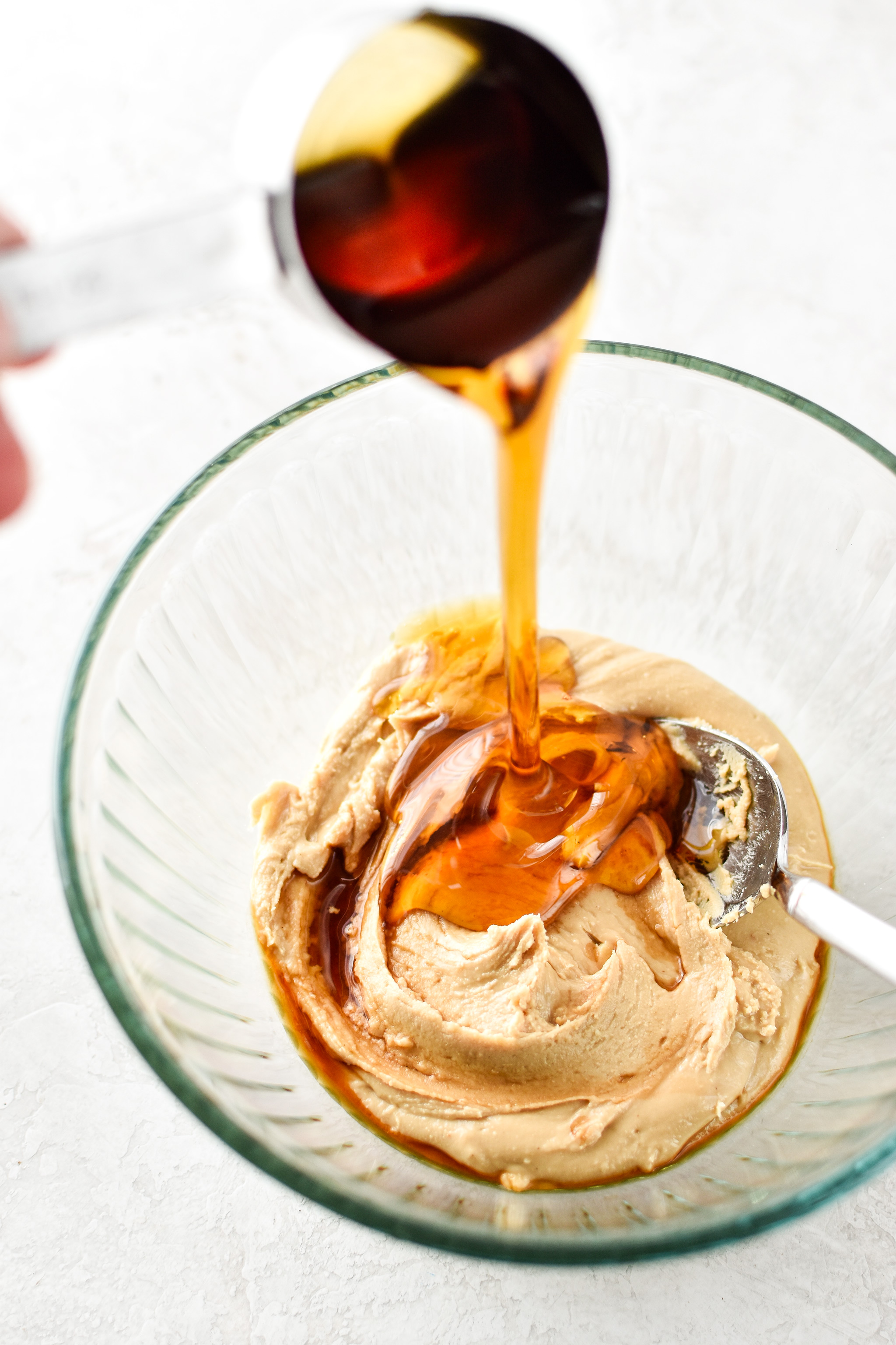 Adding maple syrup to the bowl to make Espresso Crunch Cashew Butter Cups.