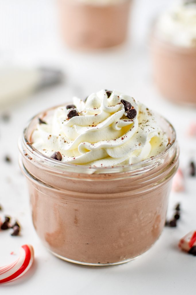 chocolate greek yogurt in a small mason jar with whipped cream and mini chocolate chips on top.