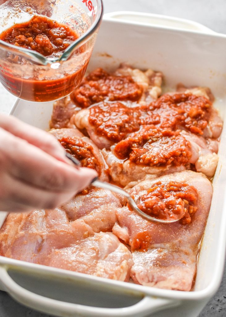 spooning salsa onto the chicken thighs before cooking the simple baked salsa chicken thighs.