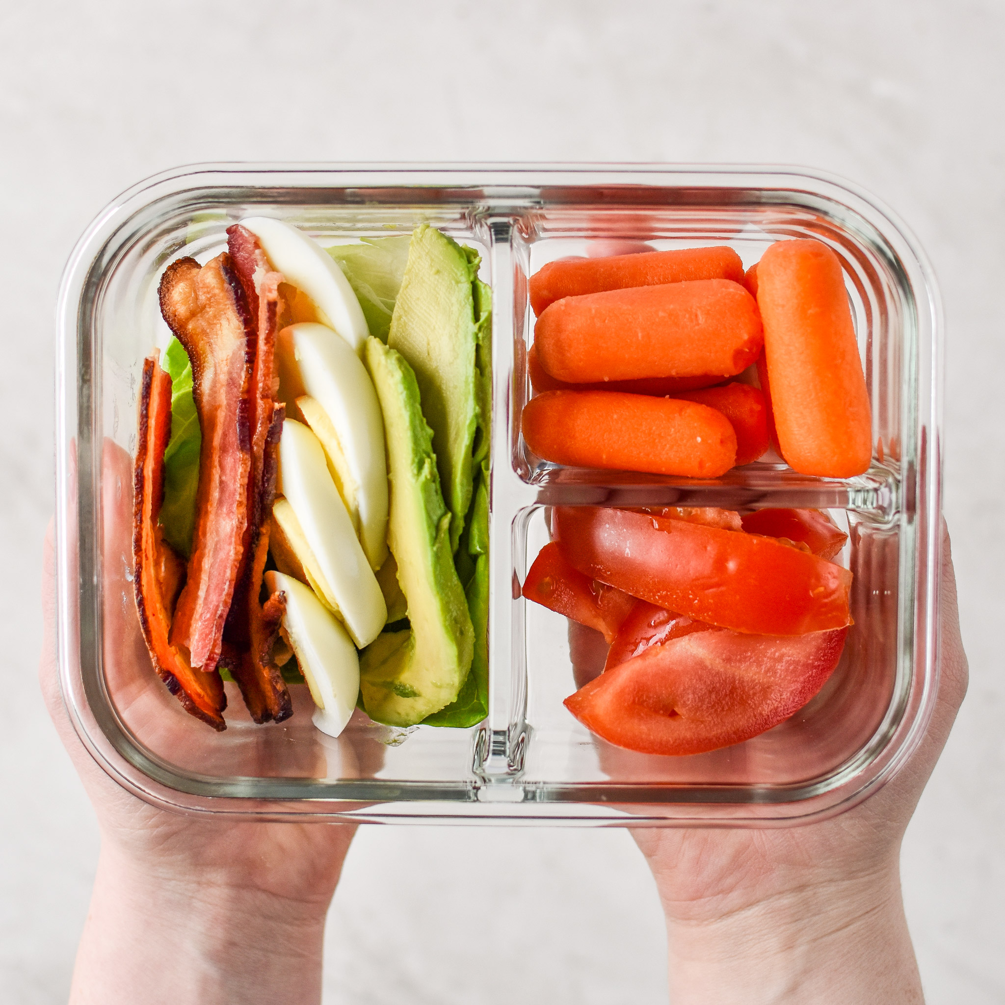 Holding a BLTA lettuce wraps meal prep in hand ready to eat.