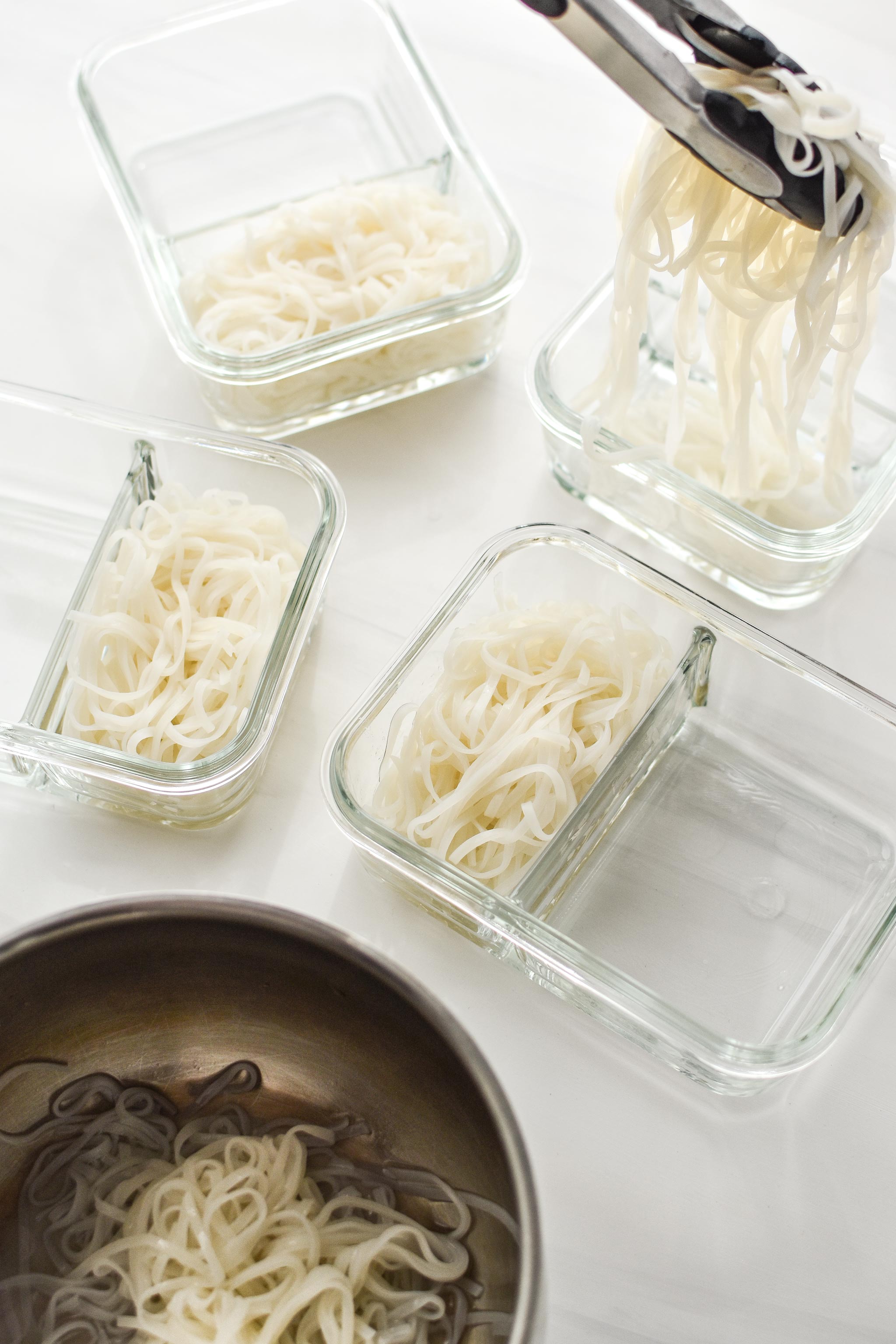 Adding the noodles to the meal prep dishes for the slow cooker peanut chicken meal prep