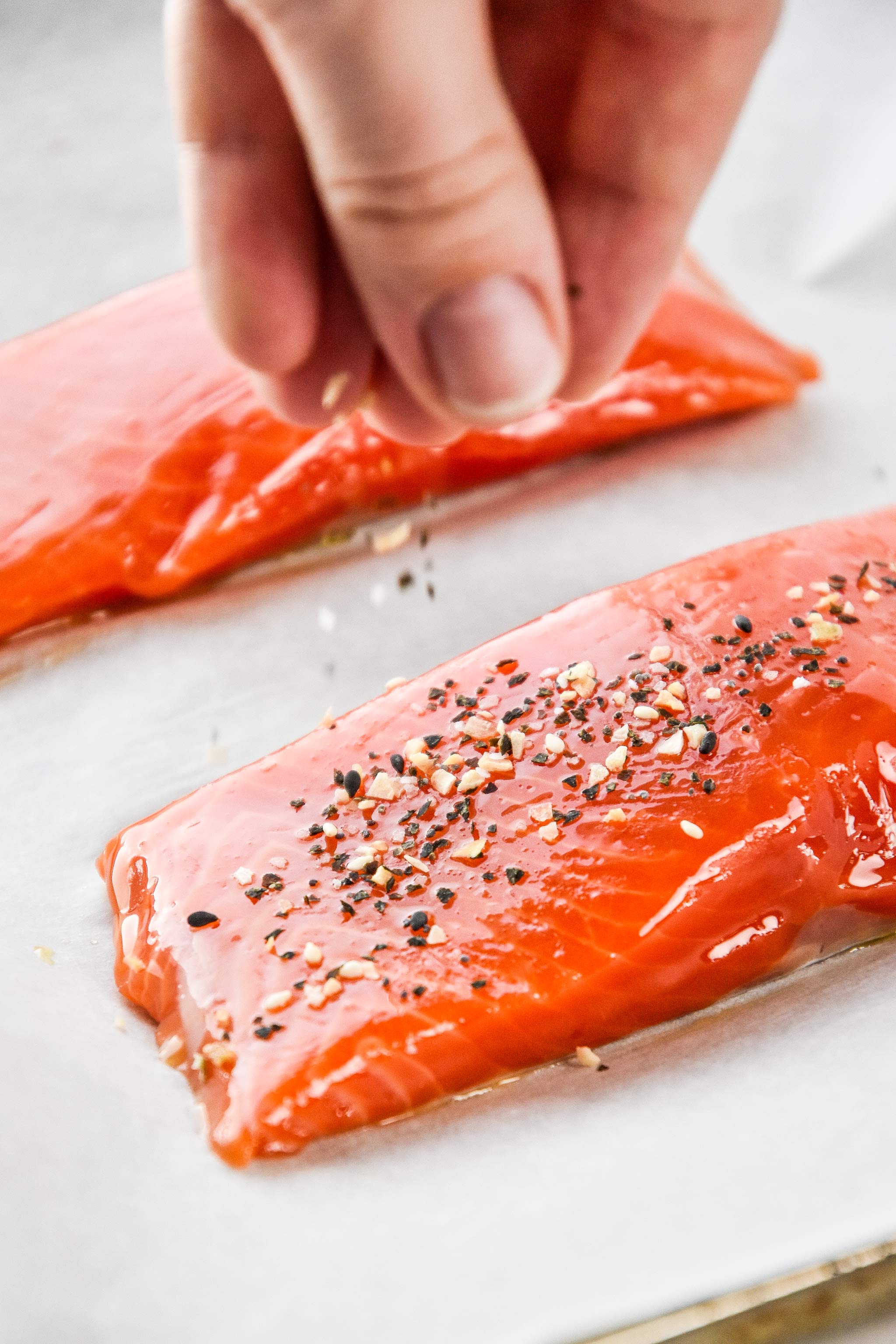 sprinkling everything but the bagel seasoning on the salmon filets