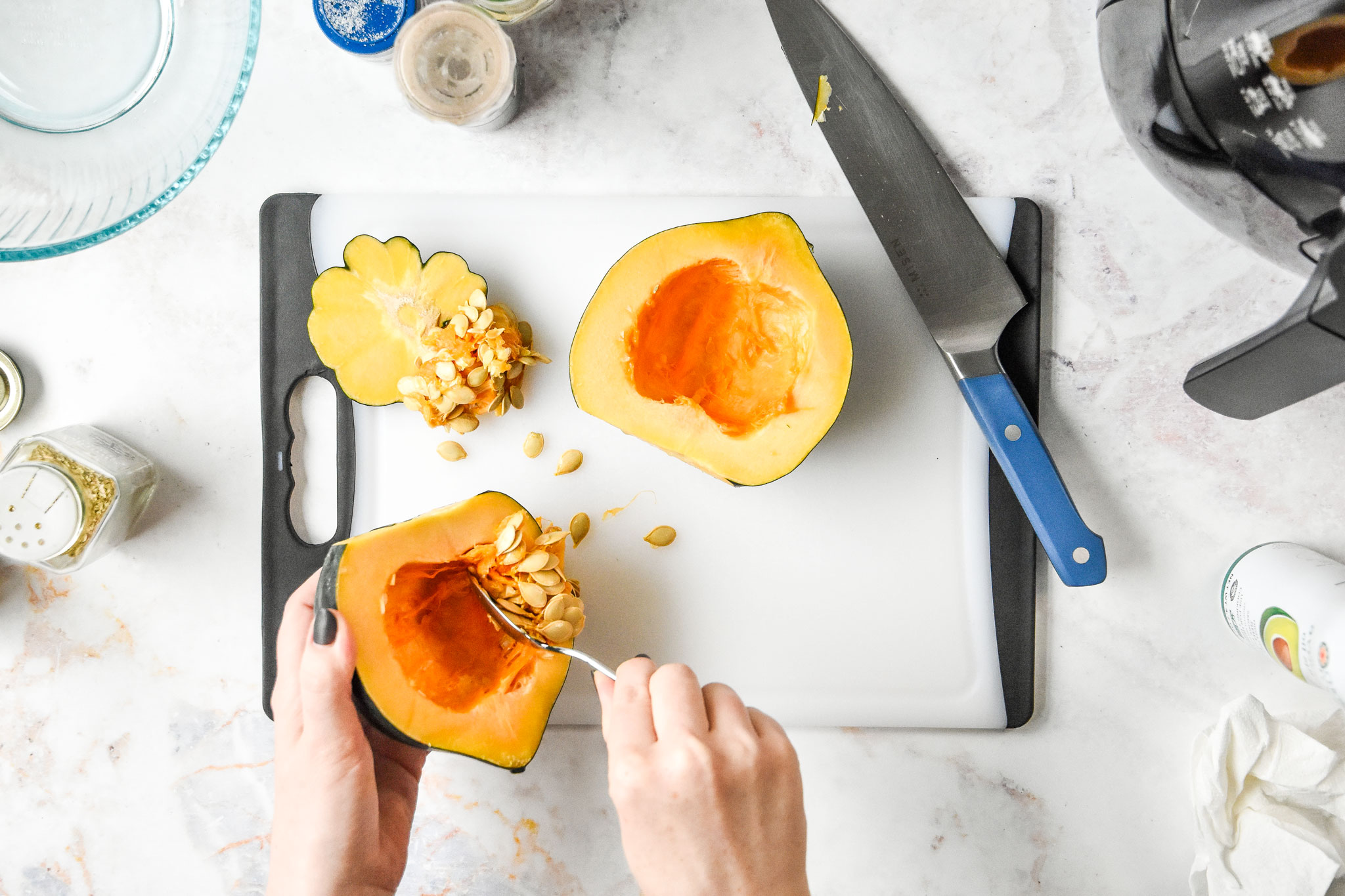 removing seeds from an acorn squash with a spoon.