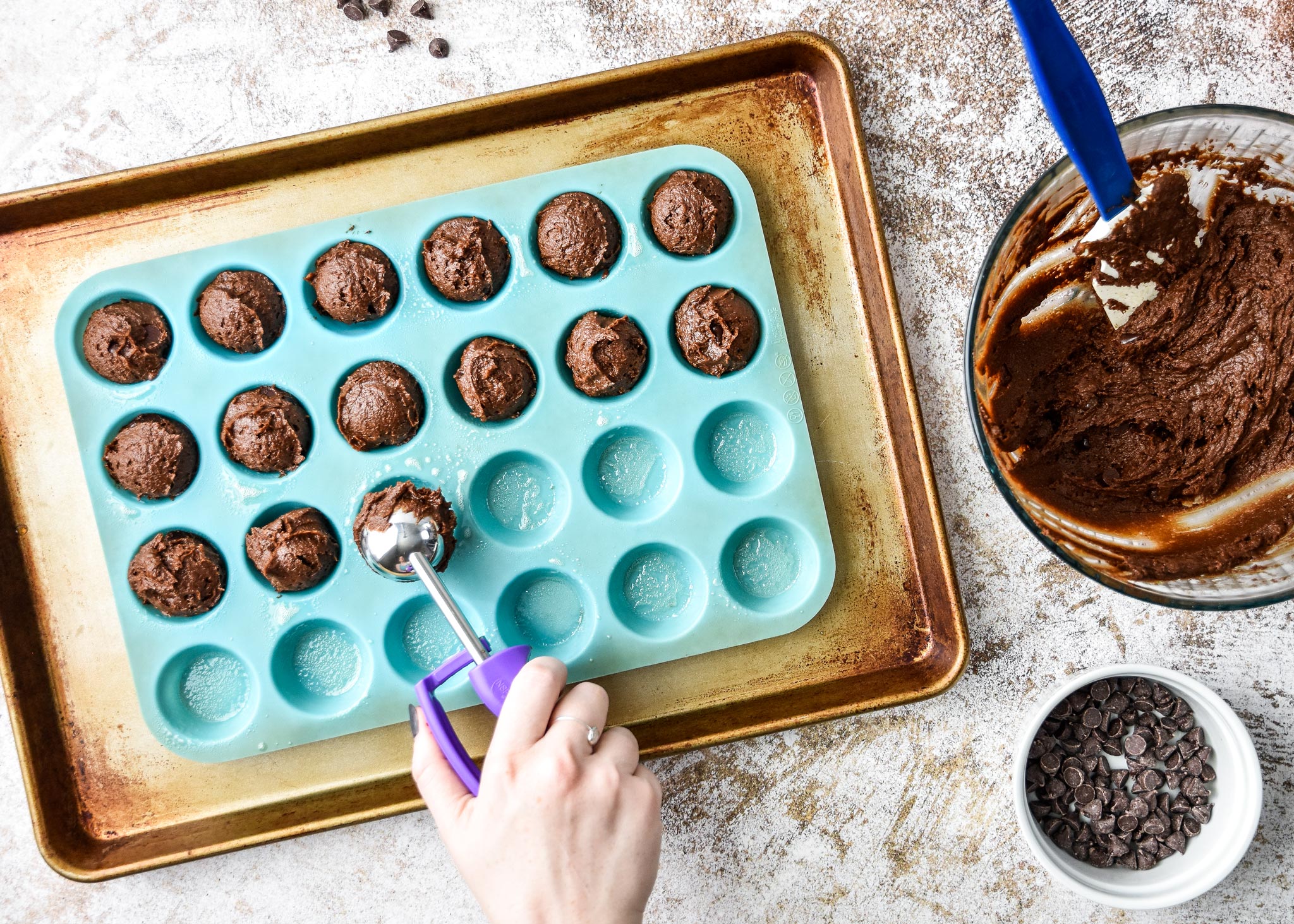scooping pumpkin spice brownie batter into the mini muffin pan