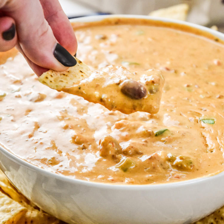 dipping a chip into the chili cheese dip.