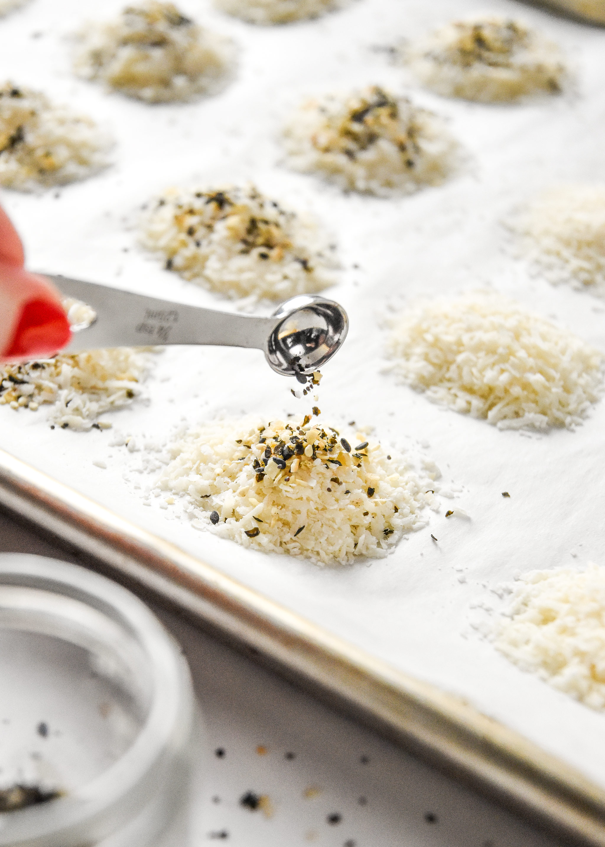 pouring everything bagel seasoning on the parmesan cheese piles
