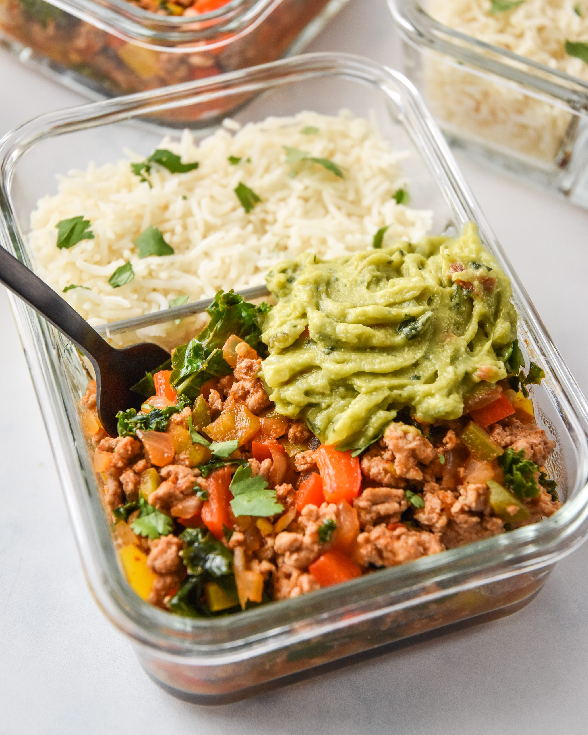 chipotle ground turkey skillet meal prep in a glass container with smashed avocado.