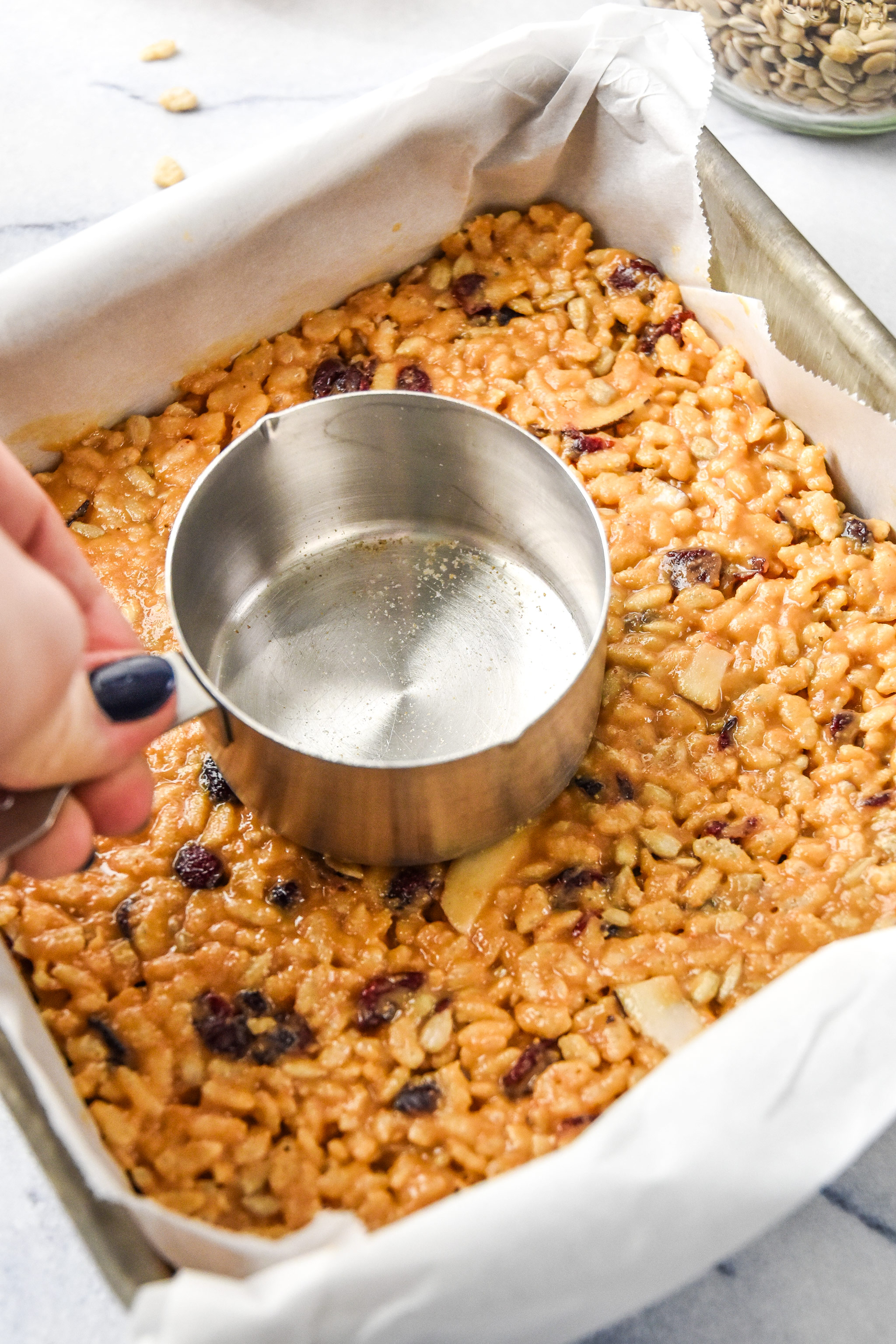 pressing the mixture for the rice krispie breakfast bars into the dish