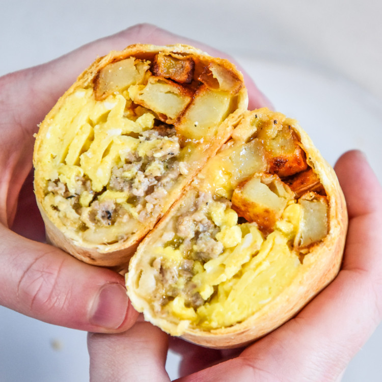 crispy air fryer breakfast burritos held in hand.