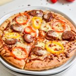 sausage and pepper personal pizzas cut into quarters on a plate