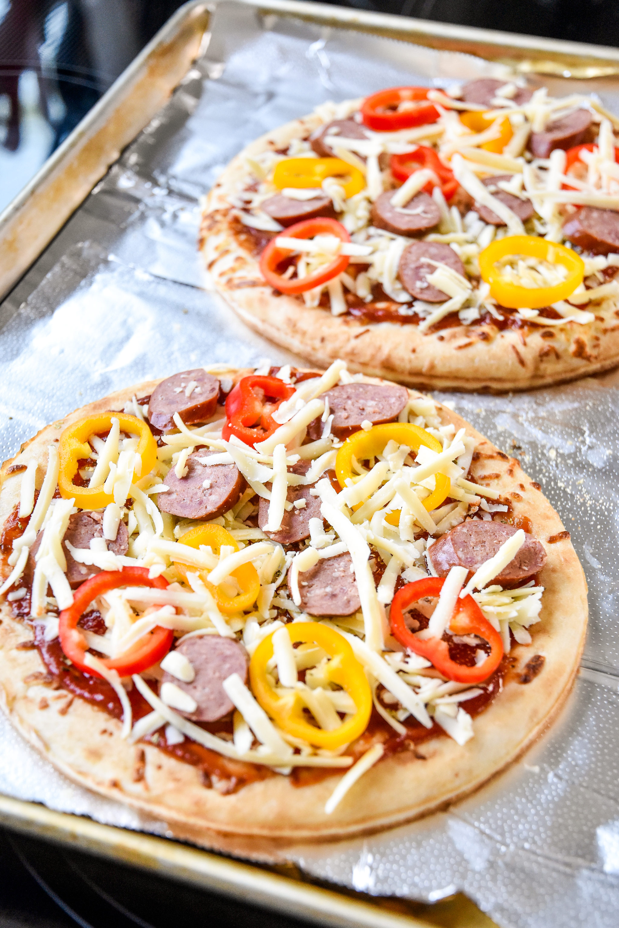 sausage and pepper personal pizzas just assembled and about to go in the oven