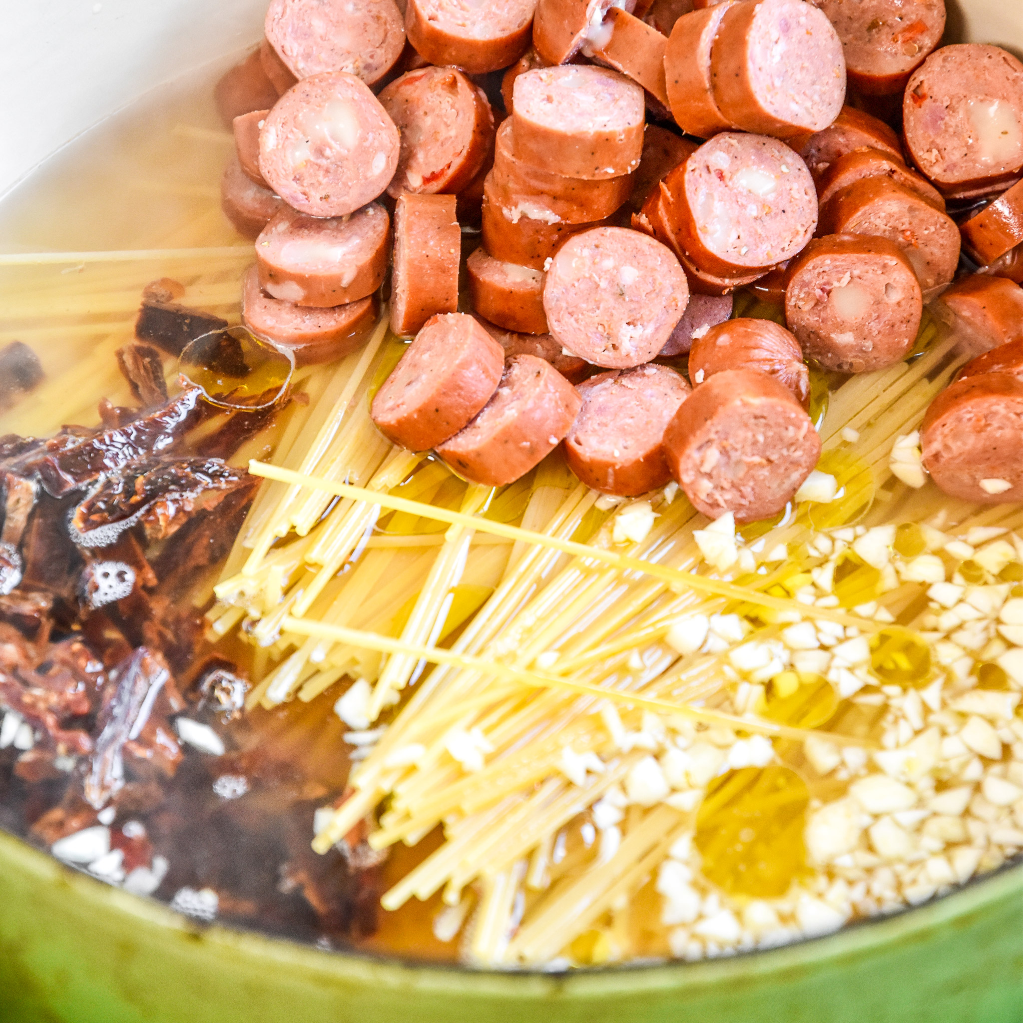 cooking the pasta, noodles, garlic and sundried tomatoes in a big pot with water