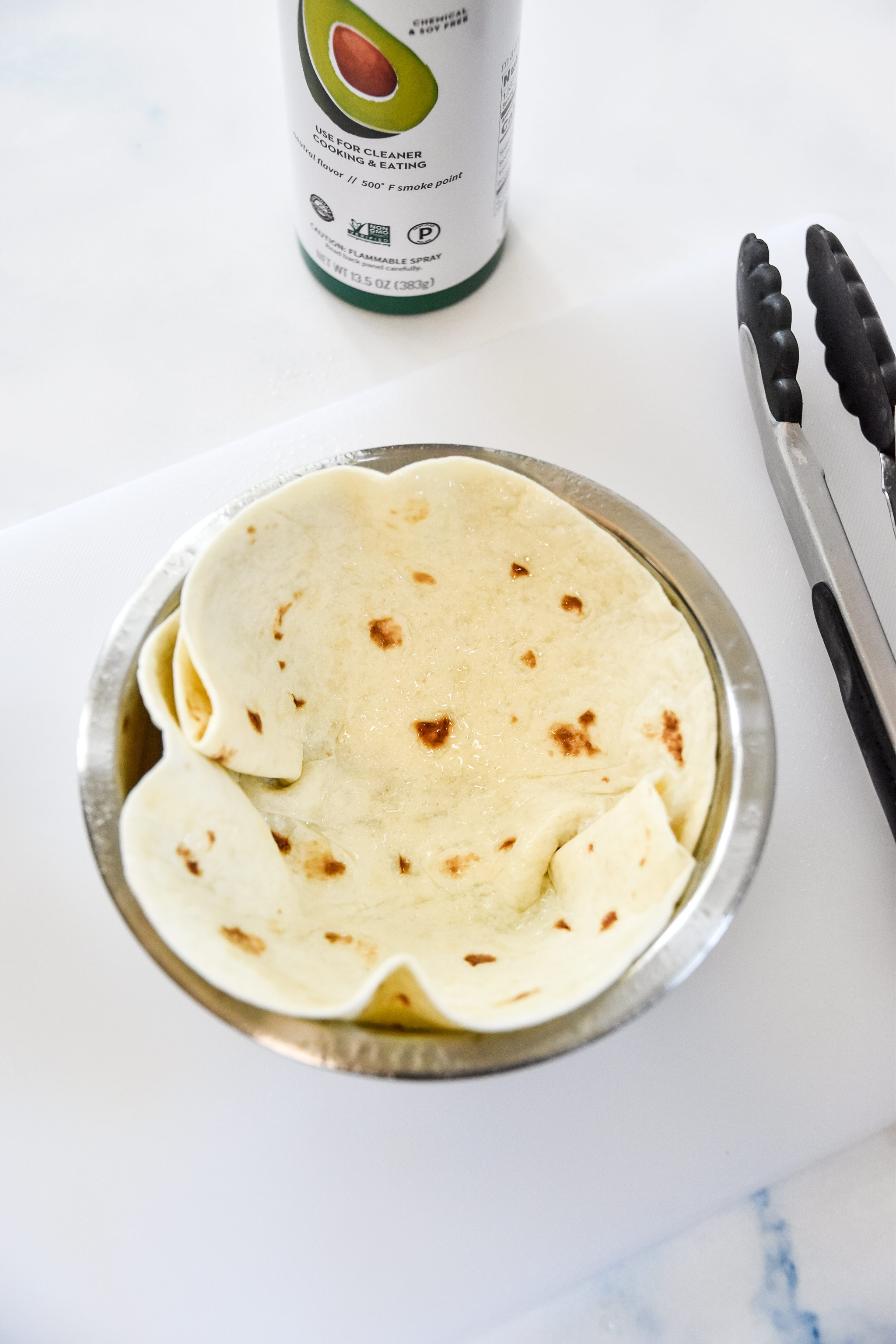 a taco size tortilla in a bowl with oil spray.