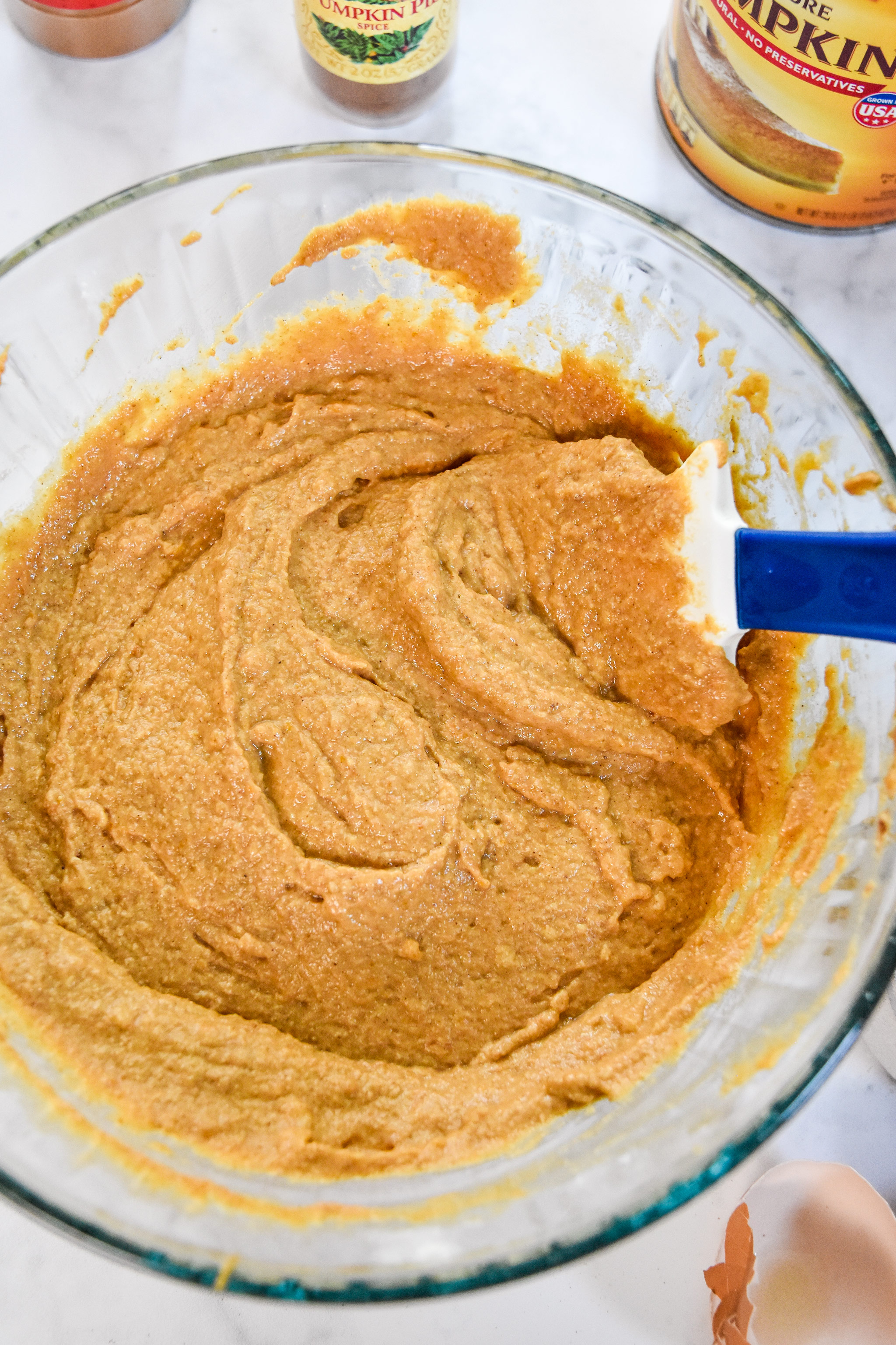 a bowl of pumpkin spice pancake mix muffin batter with a rubber spatula