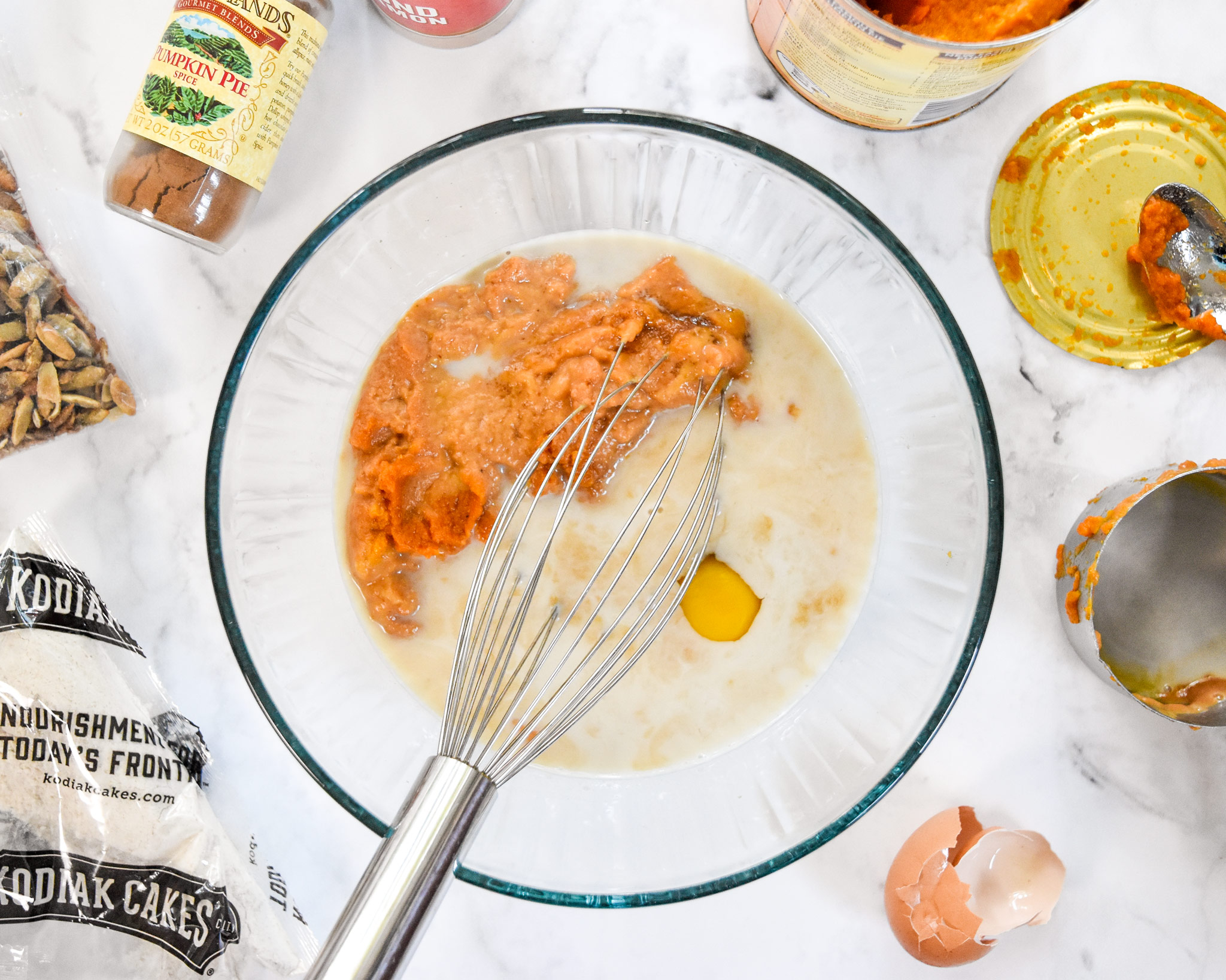 a glass bowl with wet ingredients and a metal whisk