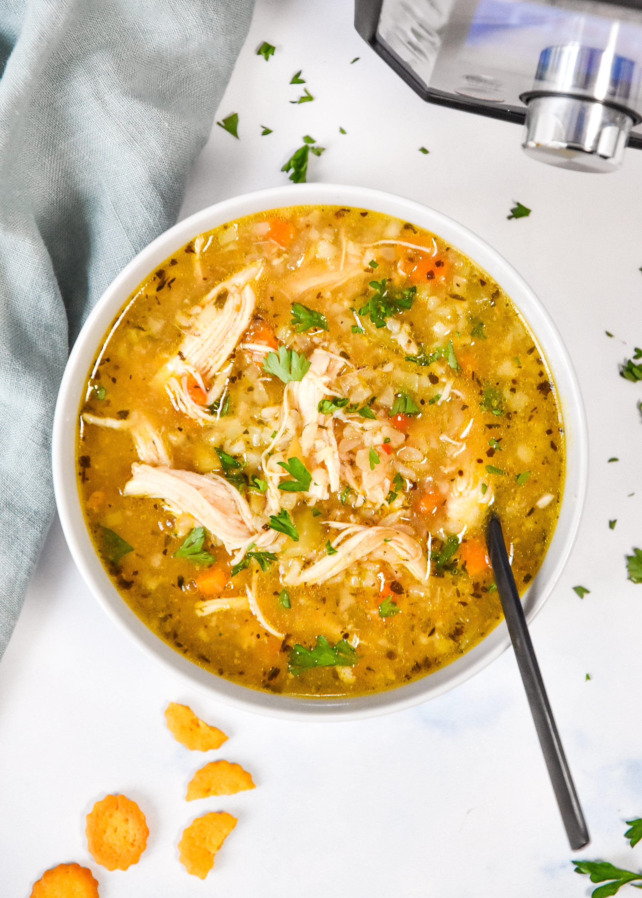instant pot ginger chicken and rice soup in a bowl with parsley on top.
