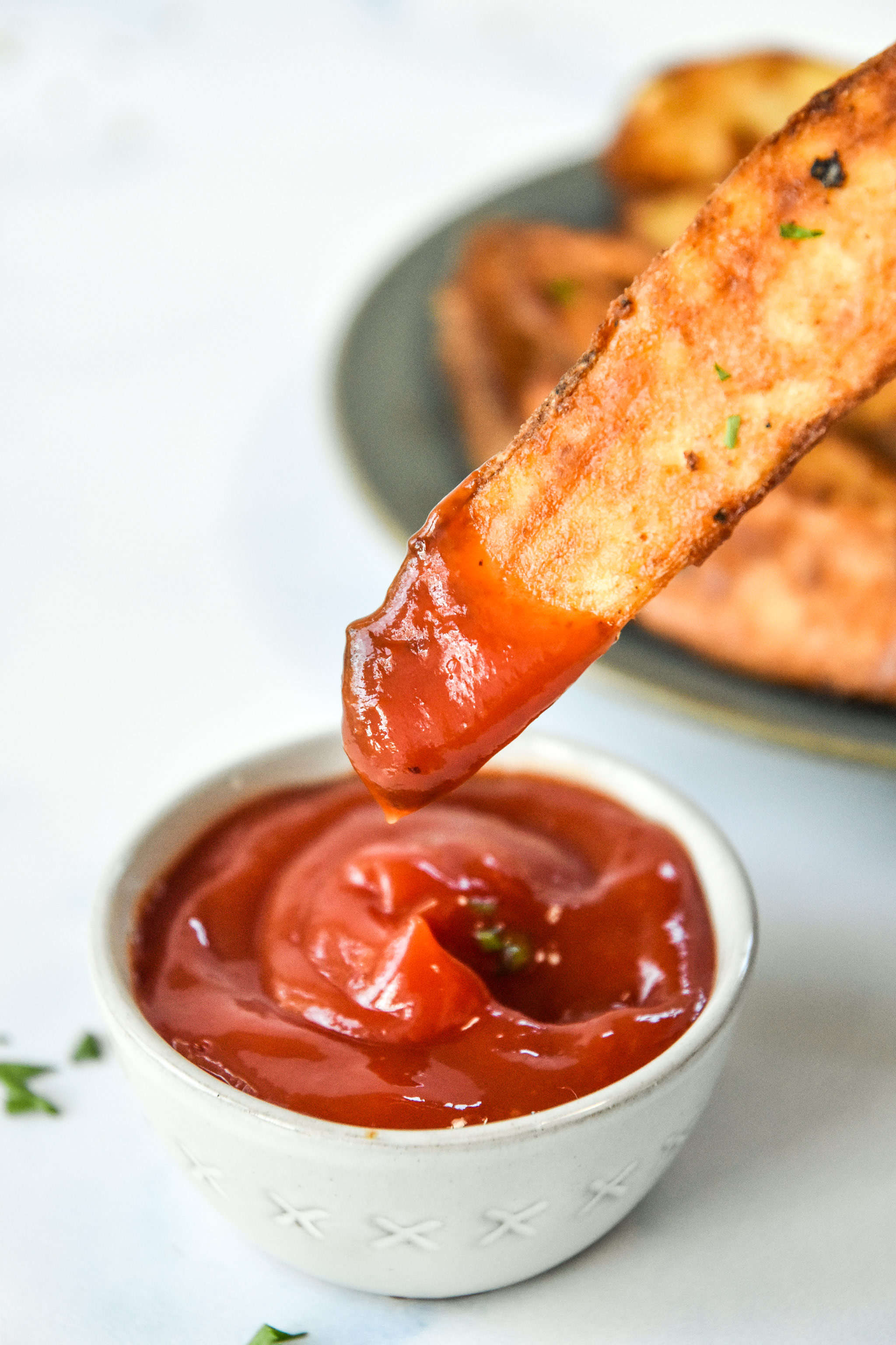 dipping a jojo potato wedges into ketchup.
