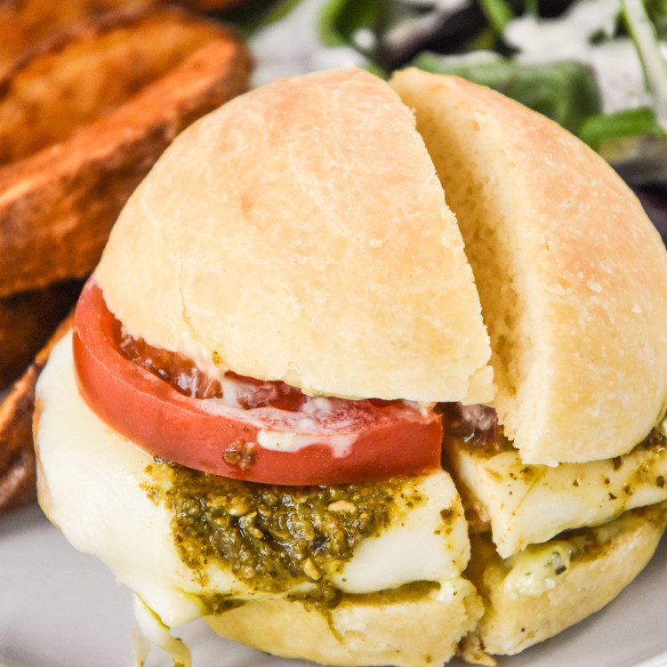 pesto chicken mozzarella sandwich with tomatoes on a plate.