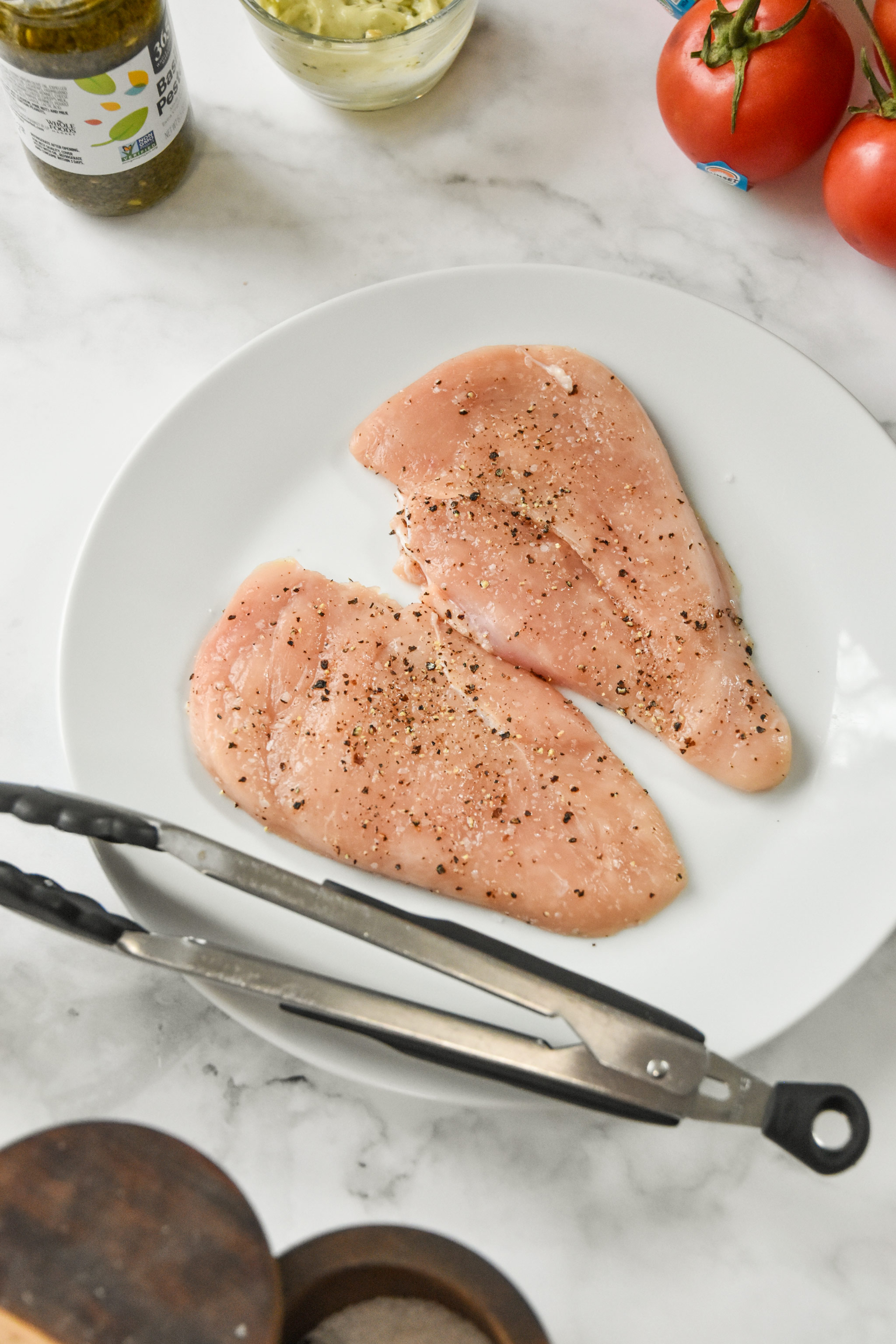 seasoned raw chicken breast on a plate.