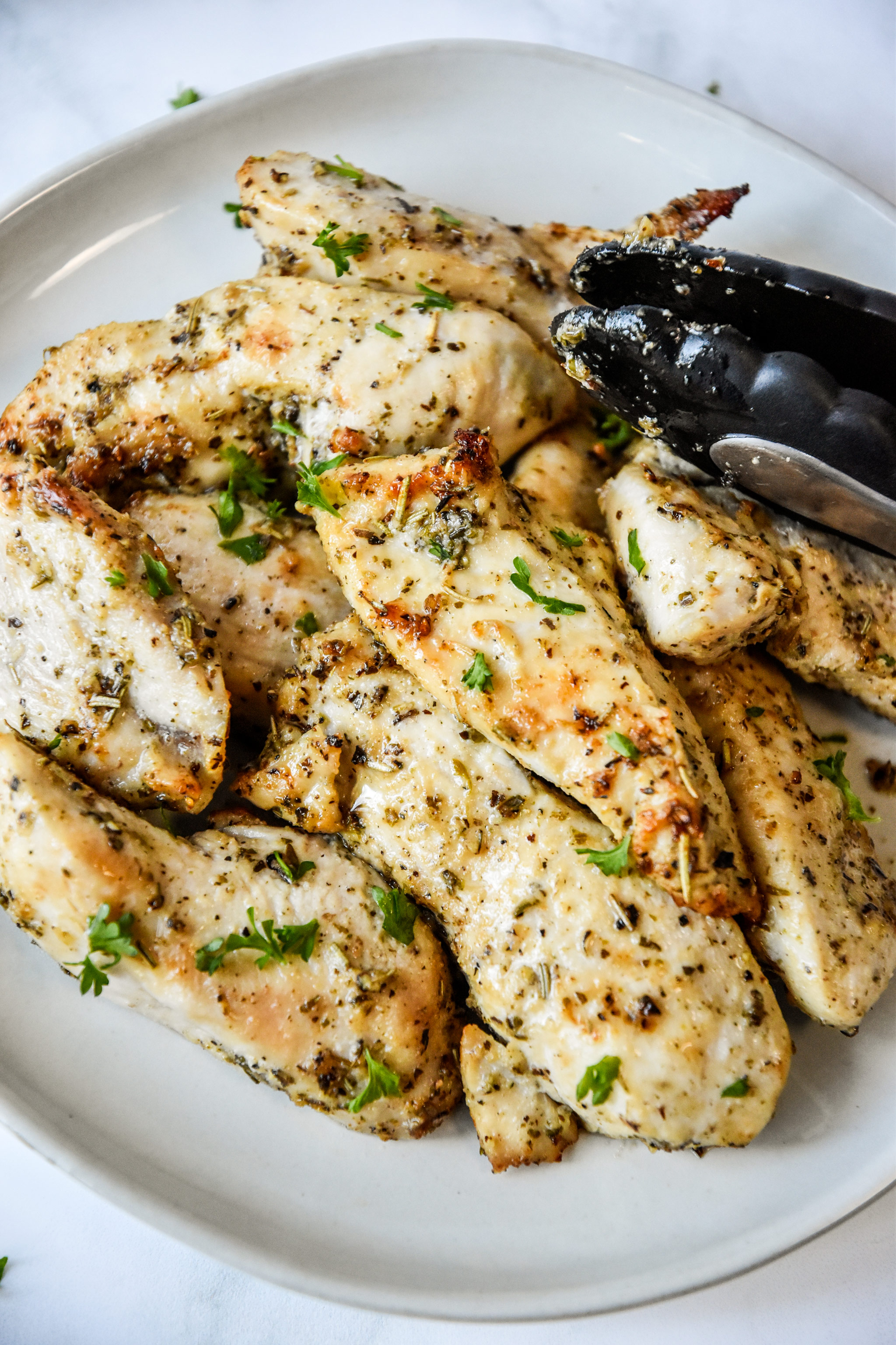 air fryer chicken tenders on a plate with tongs.