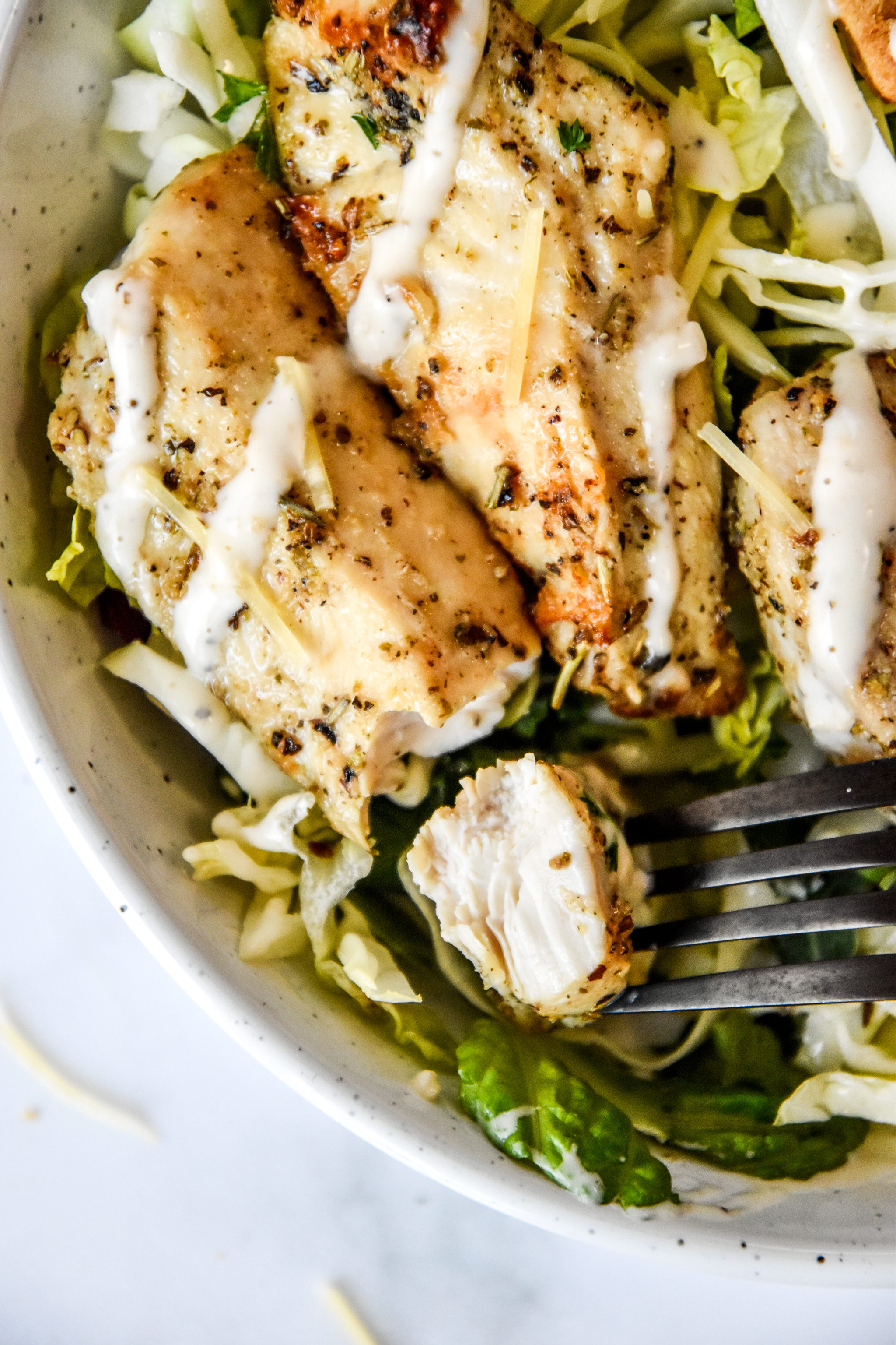 air fryer chicken tenders on a fork in a salad bowl.