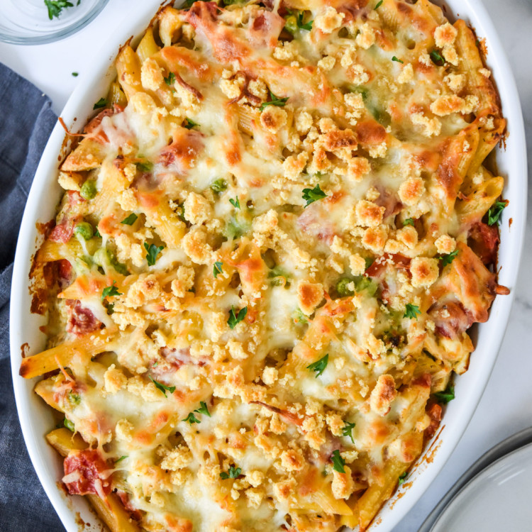 creamy pesto pasta chicken bake fresh from the oven in a white baking dish.