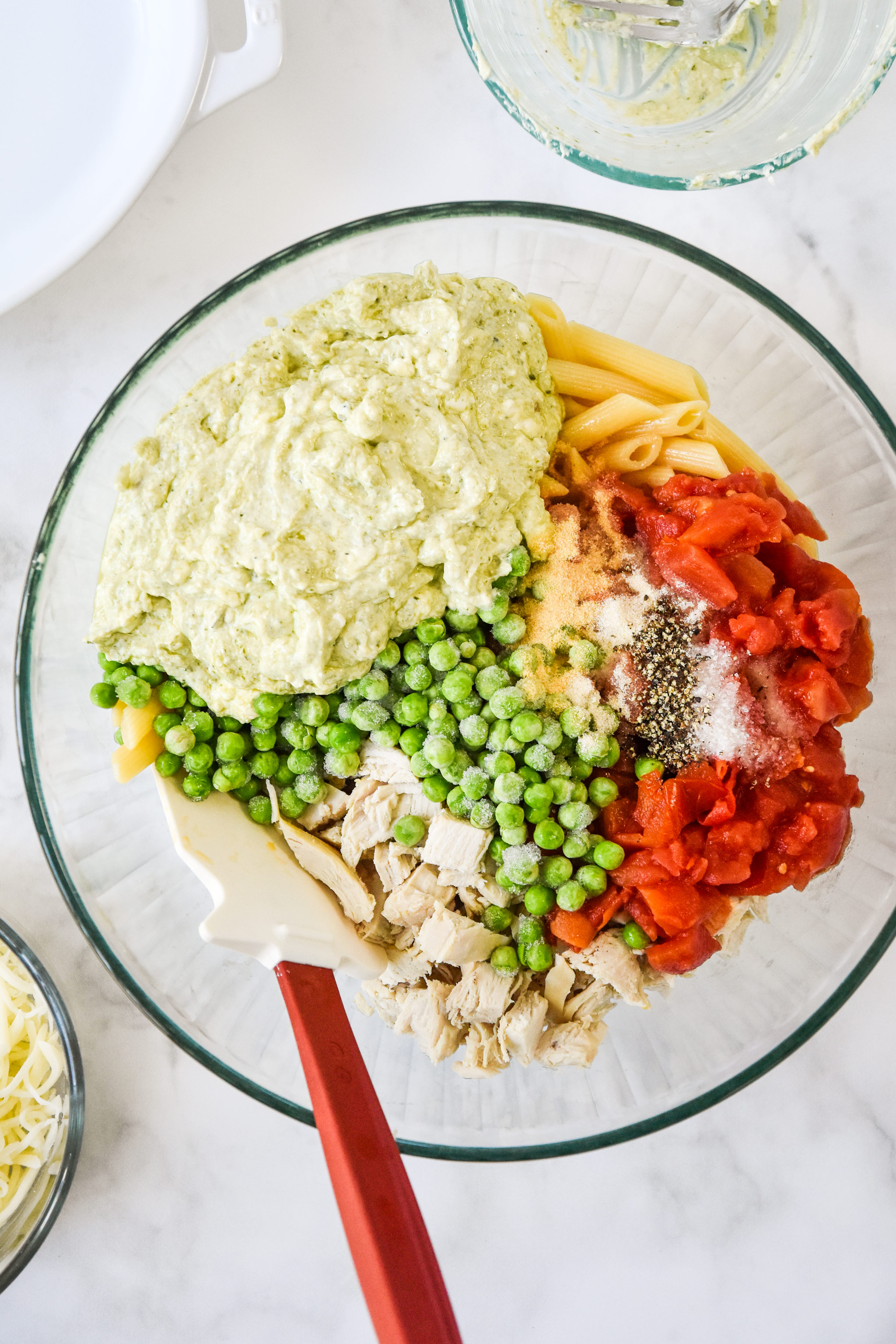 all ingredients in the big mixing bowl for the creamy pesto pasta chicken bake.