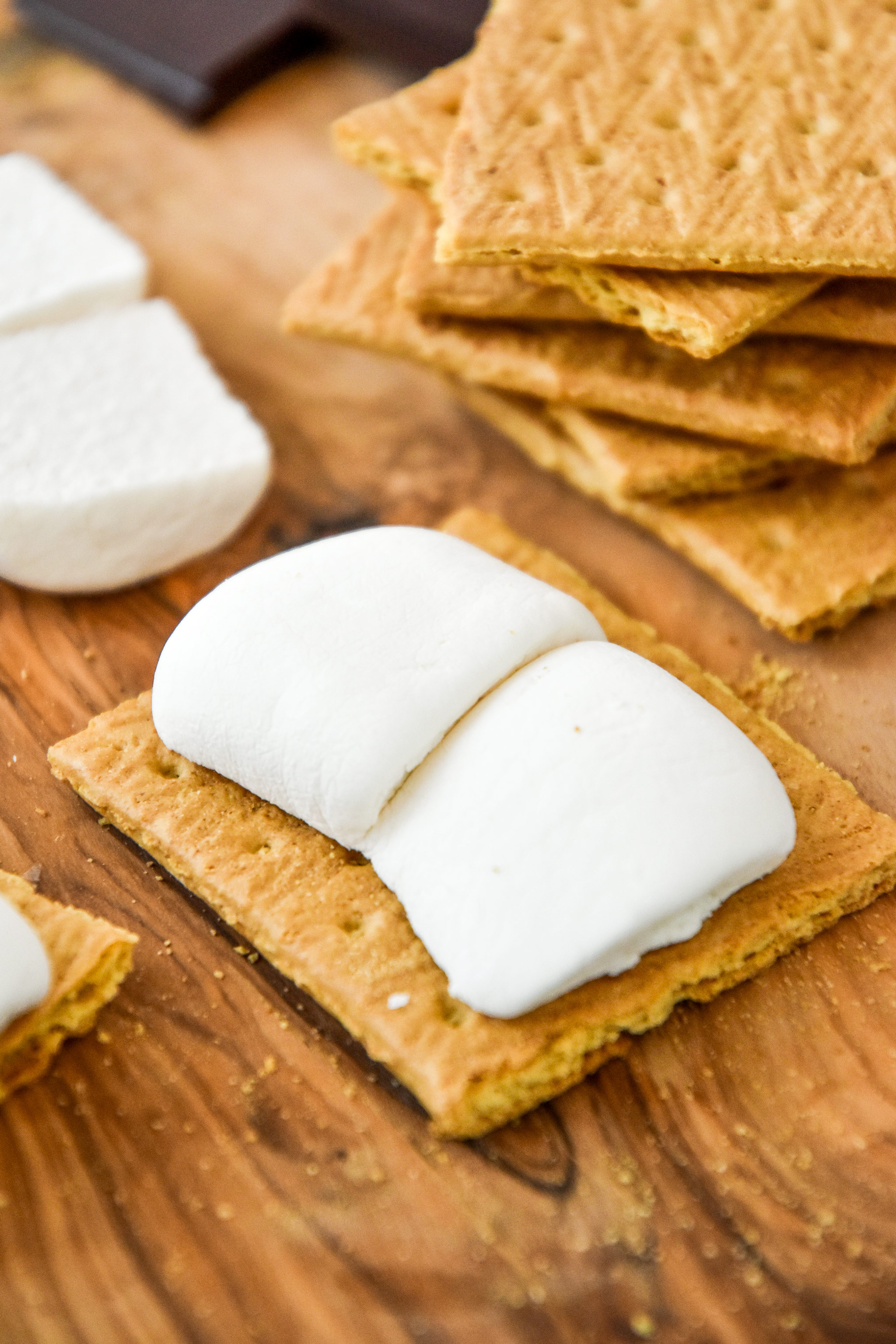two marshmallow halves on a graham cracker about to be cooked.