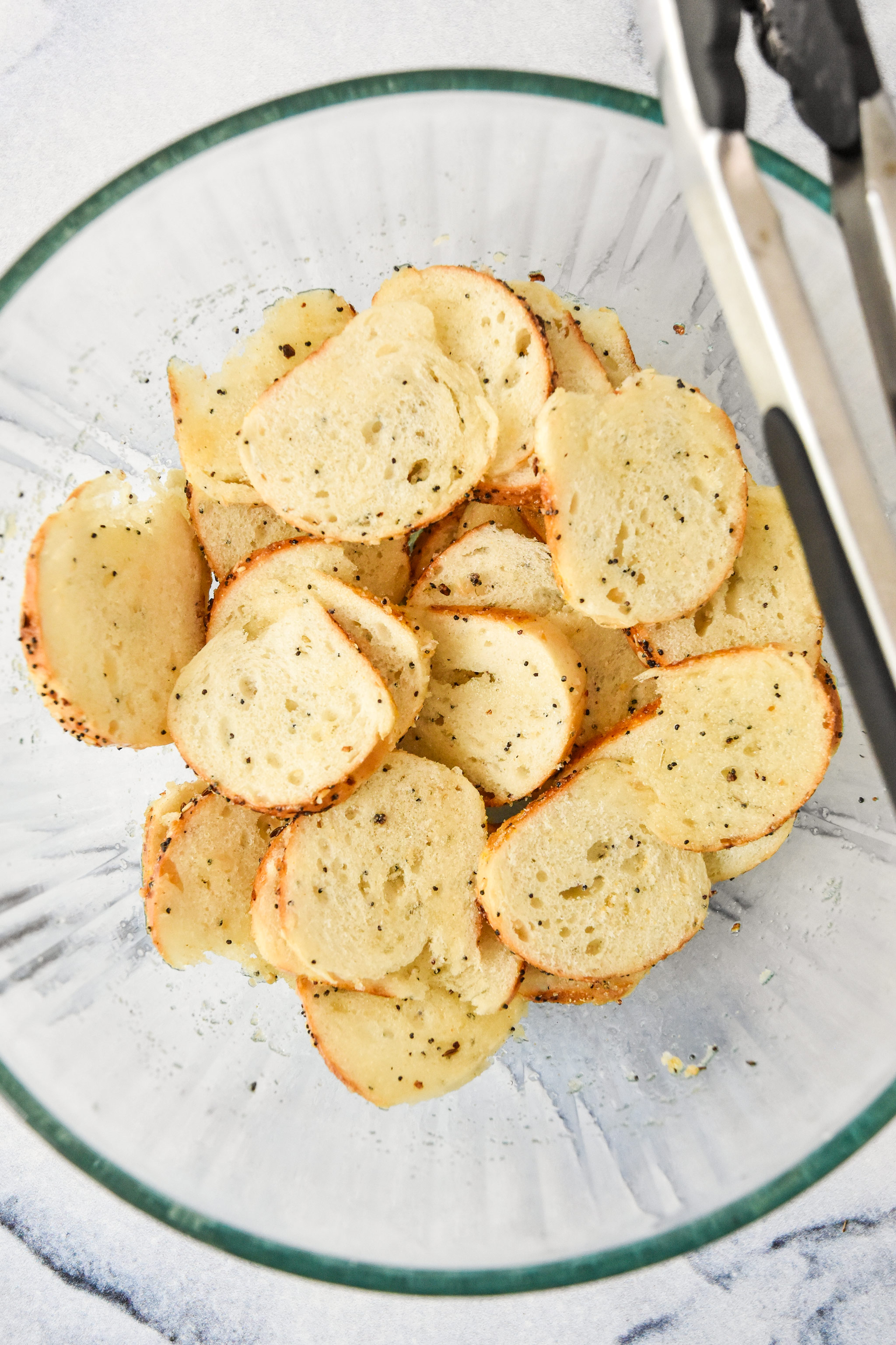 mixing bagel chip ingredients in a large glass bowl.