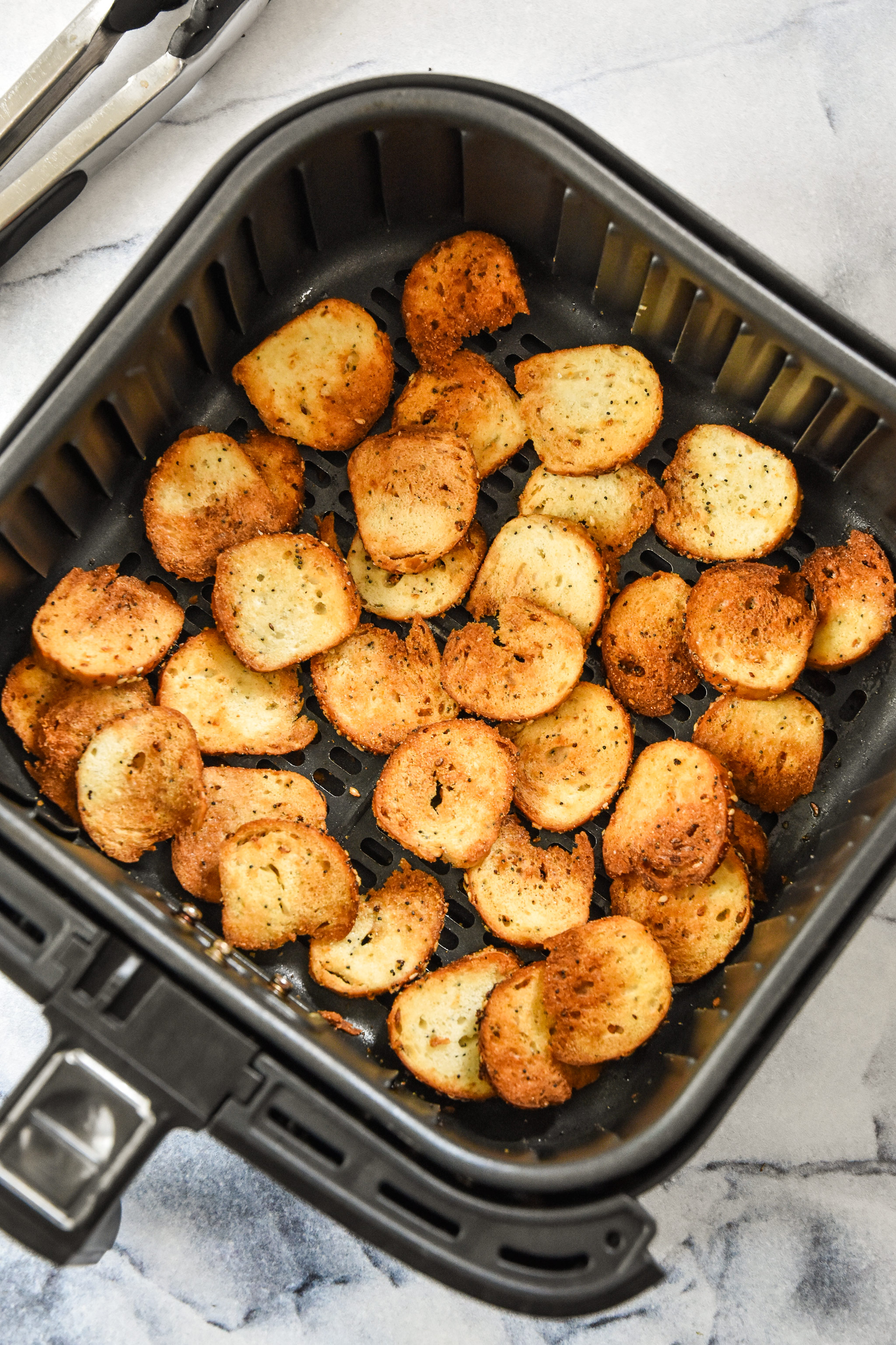 cooked bagel chips in the air fryer basket.