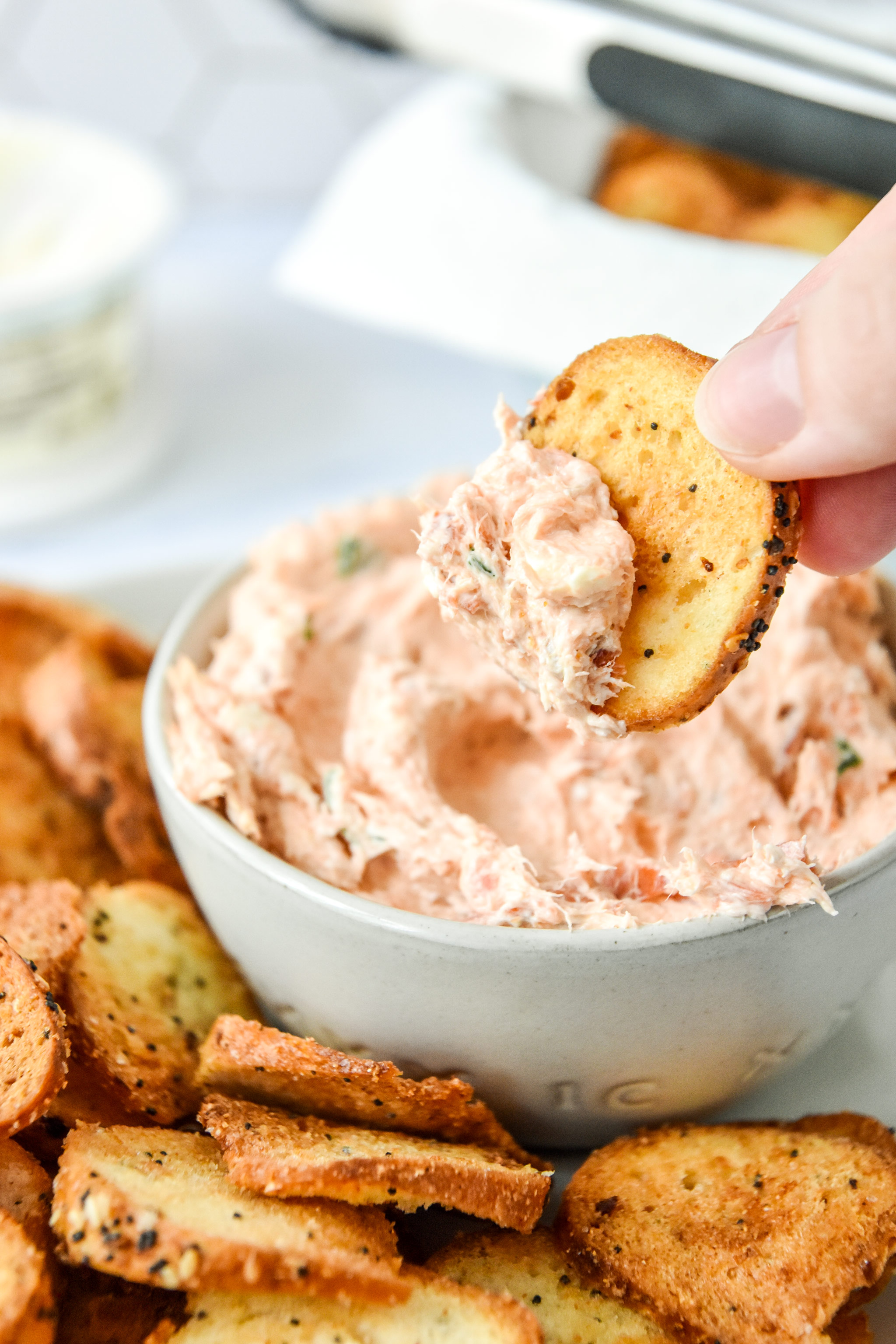 dipping the air fryer everything bagel chip into come cream cheese dip.