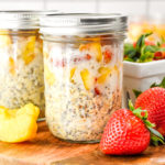 mason jar full of strawberry peach overnight oats on a cutting board.