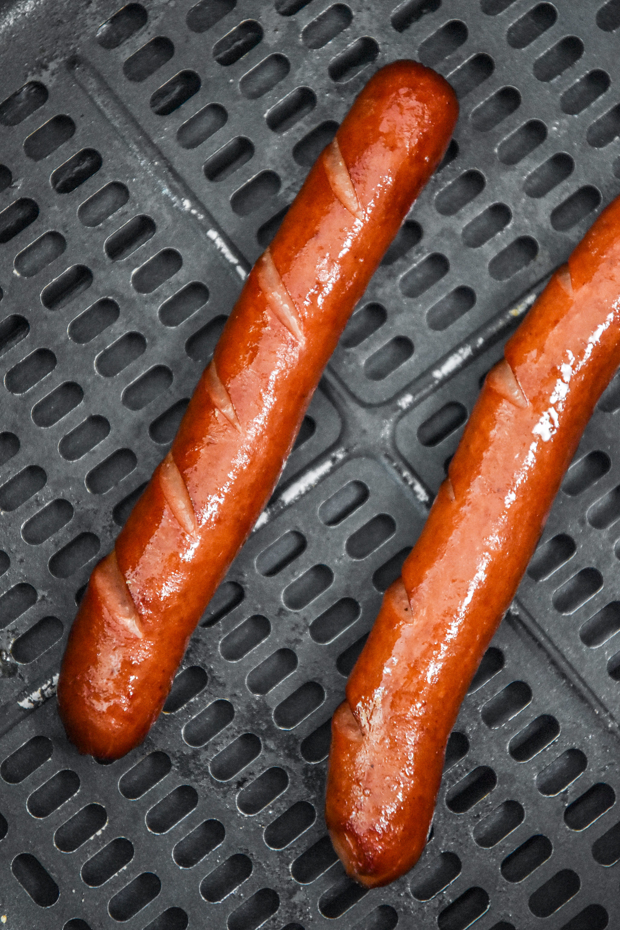 cooked hot dogs in the air fryer basket.
