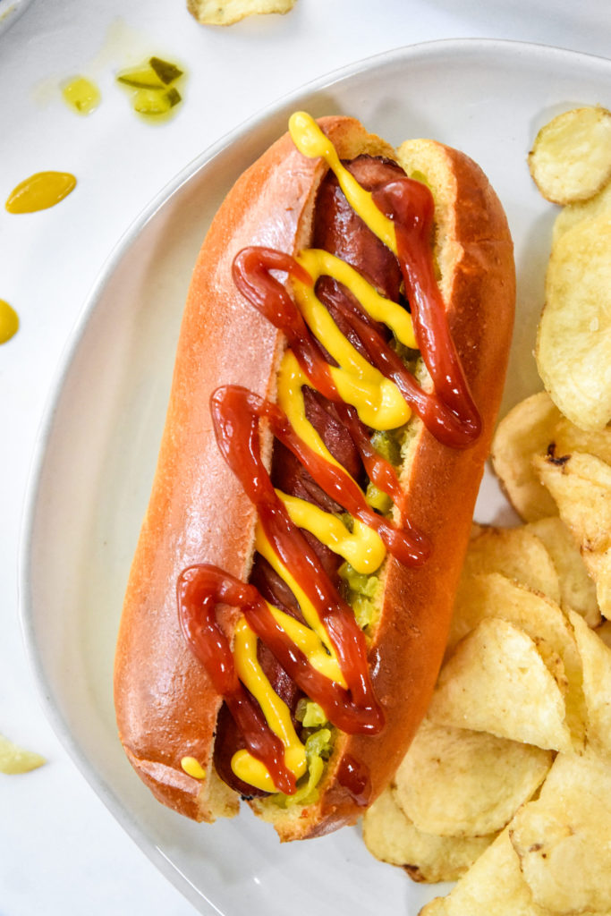 air fryer hot dogs with ketchup and mustard served with chips.
