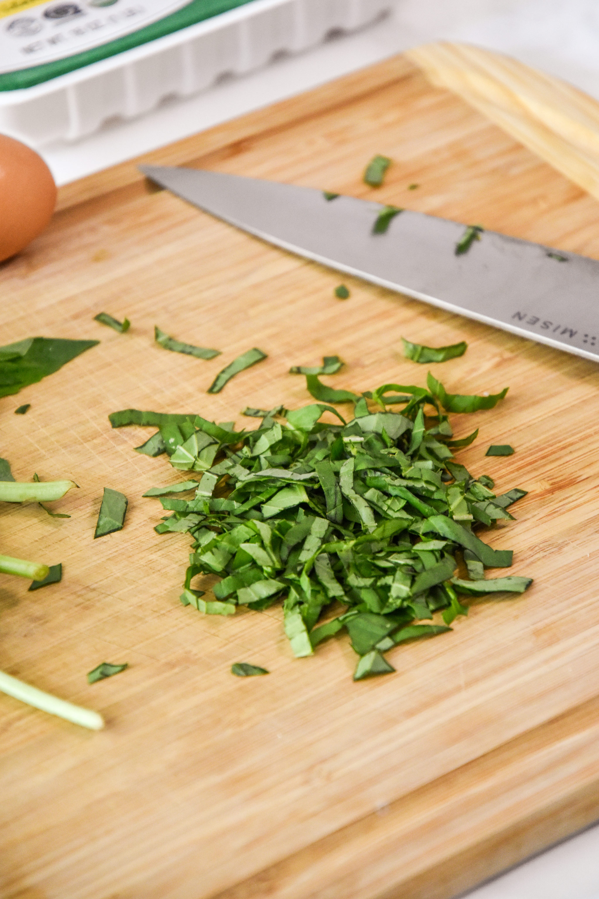 cutting fresh basil on a cutting board for the turkey burgers.