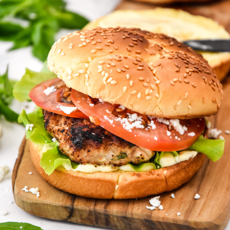 Feta Basil Turkey Burger on a bun with tomato and lettuce.