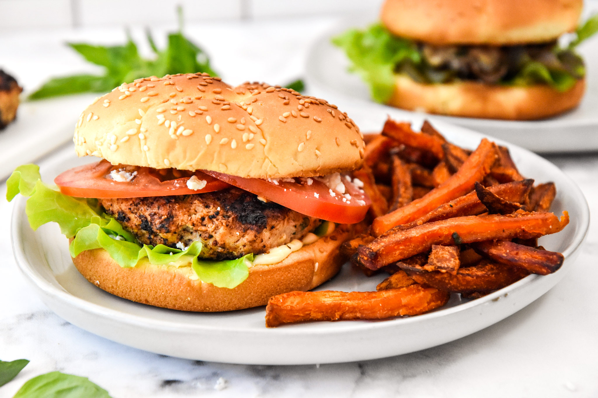 Feta basil turkey burger on a plate with sweet potato fries.