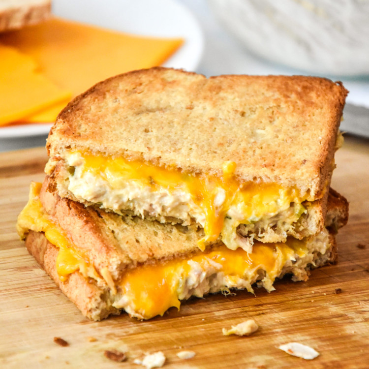 air fryer tuna melt cut in half stacked on a cutting board.