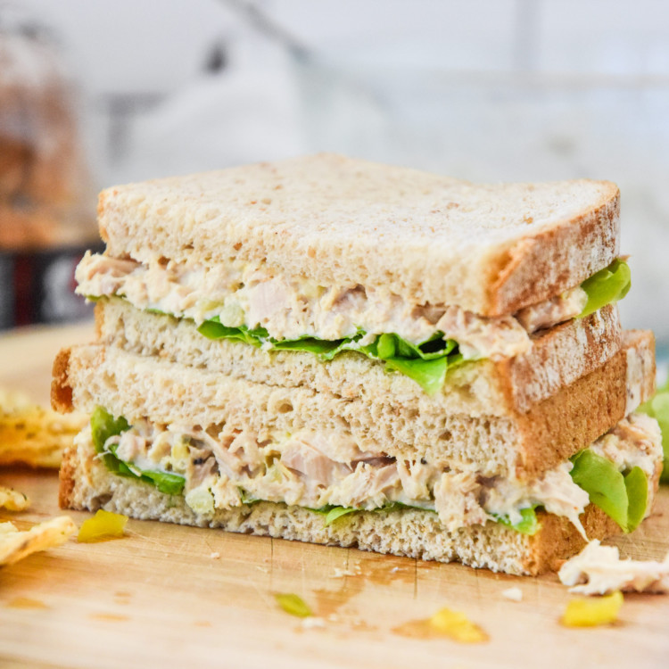lazy no chop tuna salad sandwich cut in half on a cutting board.