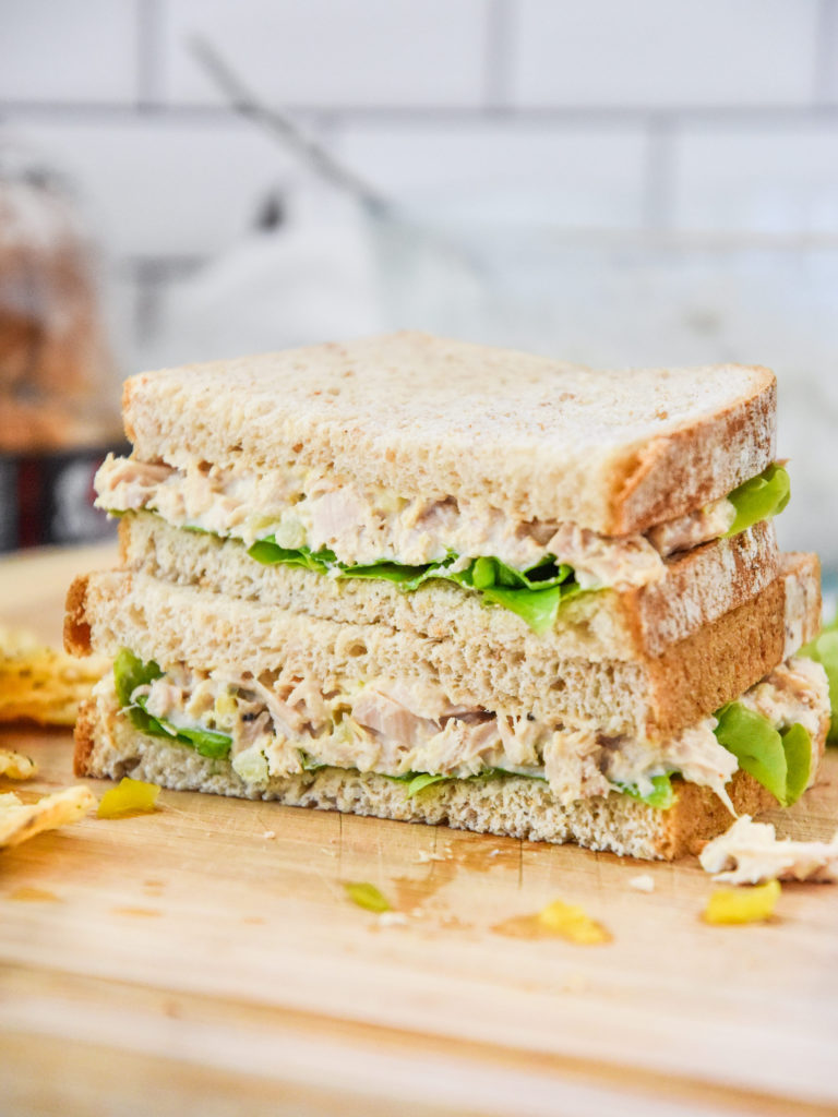 lazy no chop tuna salad sandwich cut in half on a cutting board.