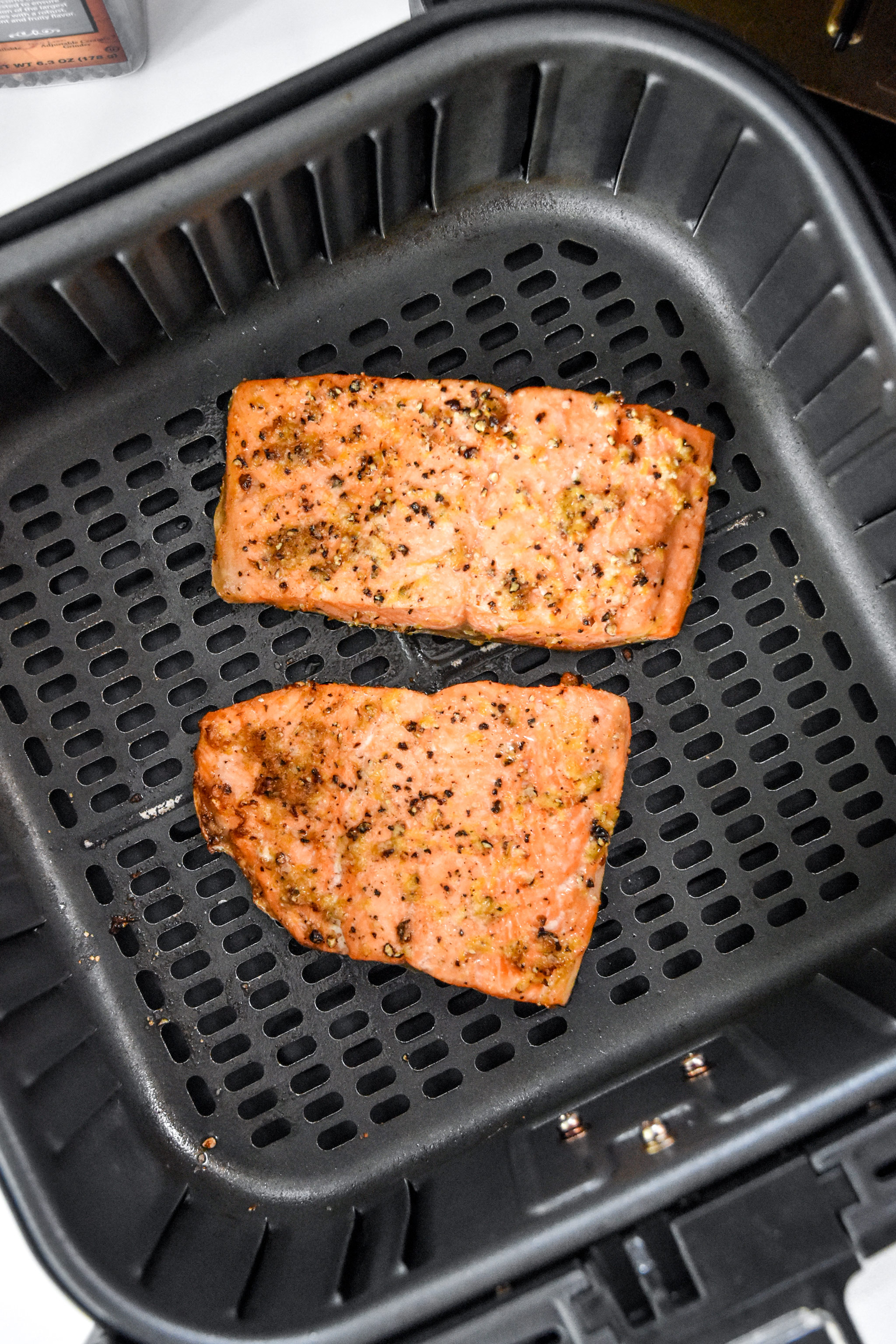 cooked air fryer lemon pepper salmon in the air fryer basket.