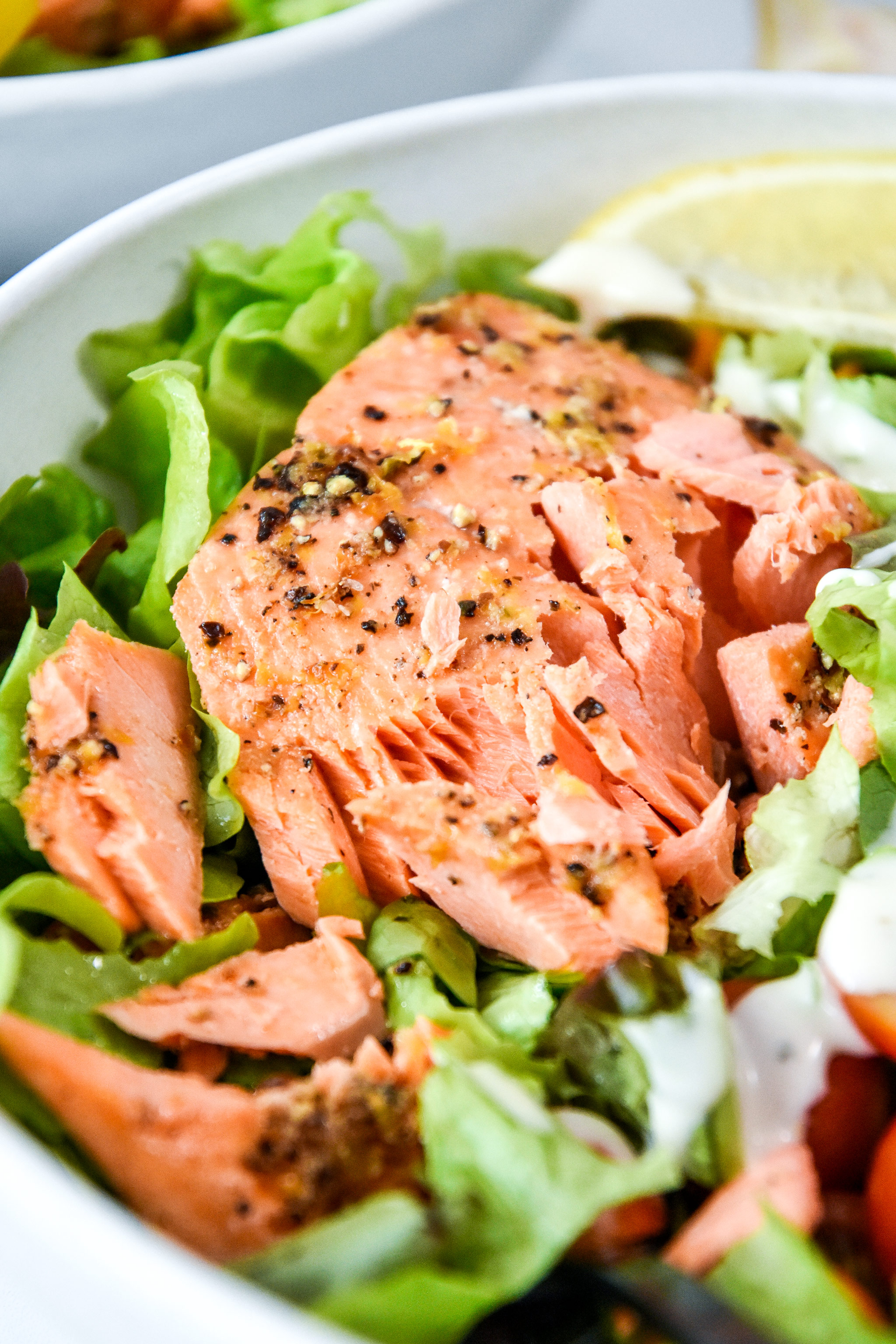 air fryer lemon pepper salmon flaked apart on a salad.