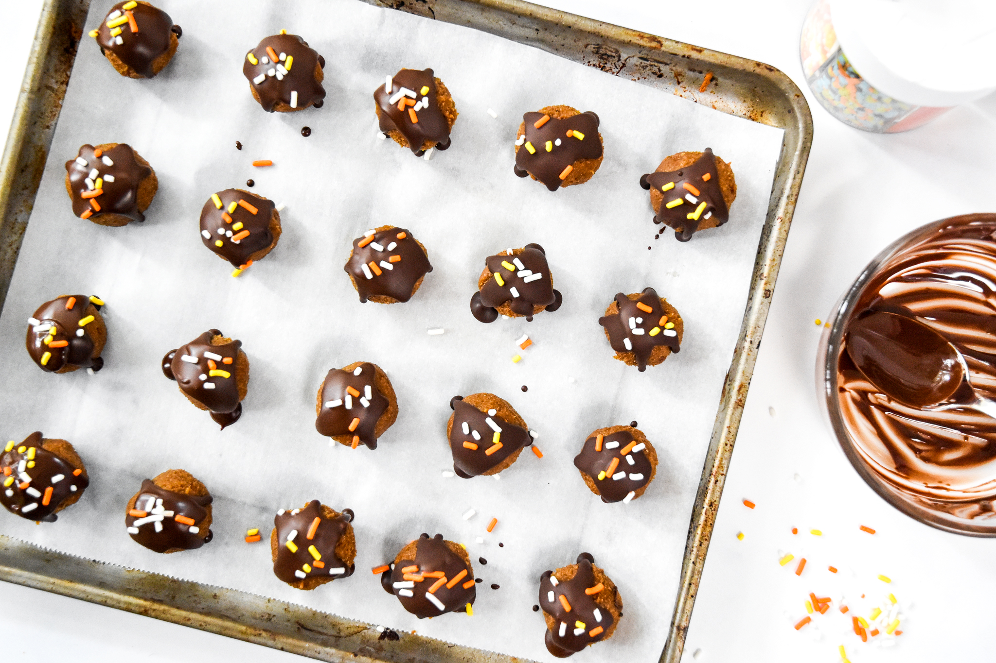 no-bake pumpkin spice date balls on a parchment lined baking sheet.