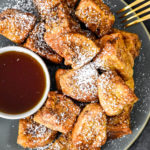 air fryer french toast bites on a plate with cup of syrup.
