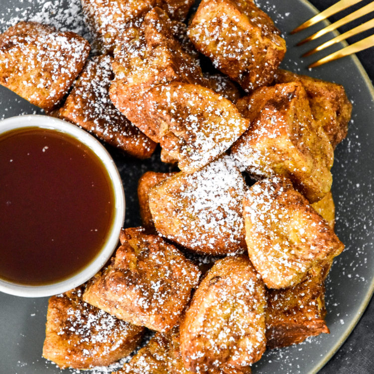 air fryer french toast bites on a plate with cup of syrup.